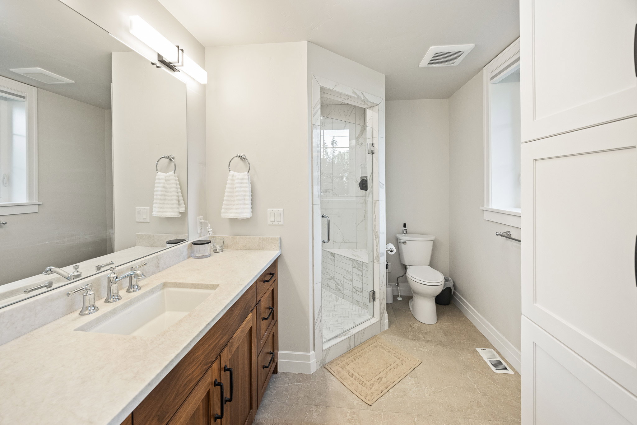 Bathroom featuring a double vanity with stone countertop, wood-finish cabinetry, and brushed nickel fixtures