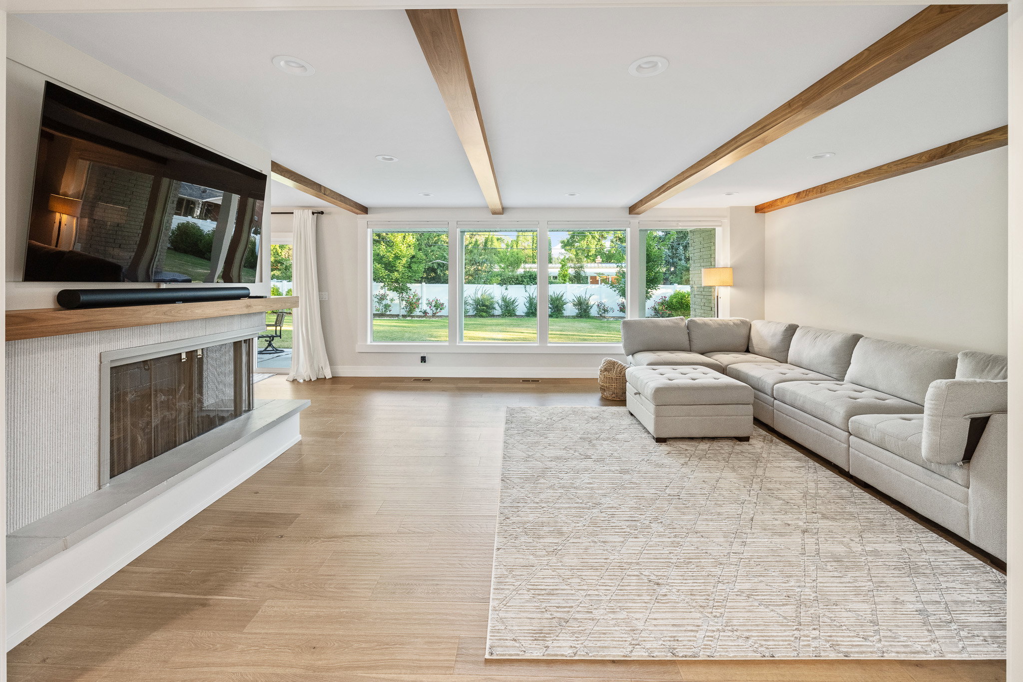 Living space featuring wood-finish flooring, exposed ceiling beams, and a fireplace with a light-toned hearth