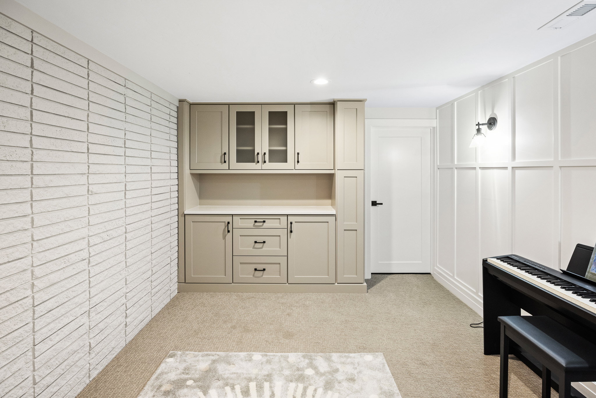 Built-in cabinetry with glass-front uppers and a light countertop, complemented by a textured brick-style wall and panel molding