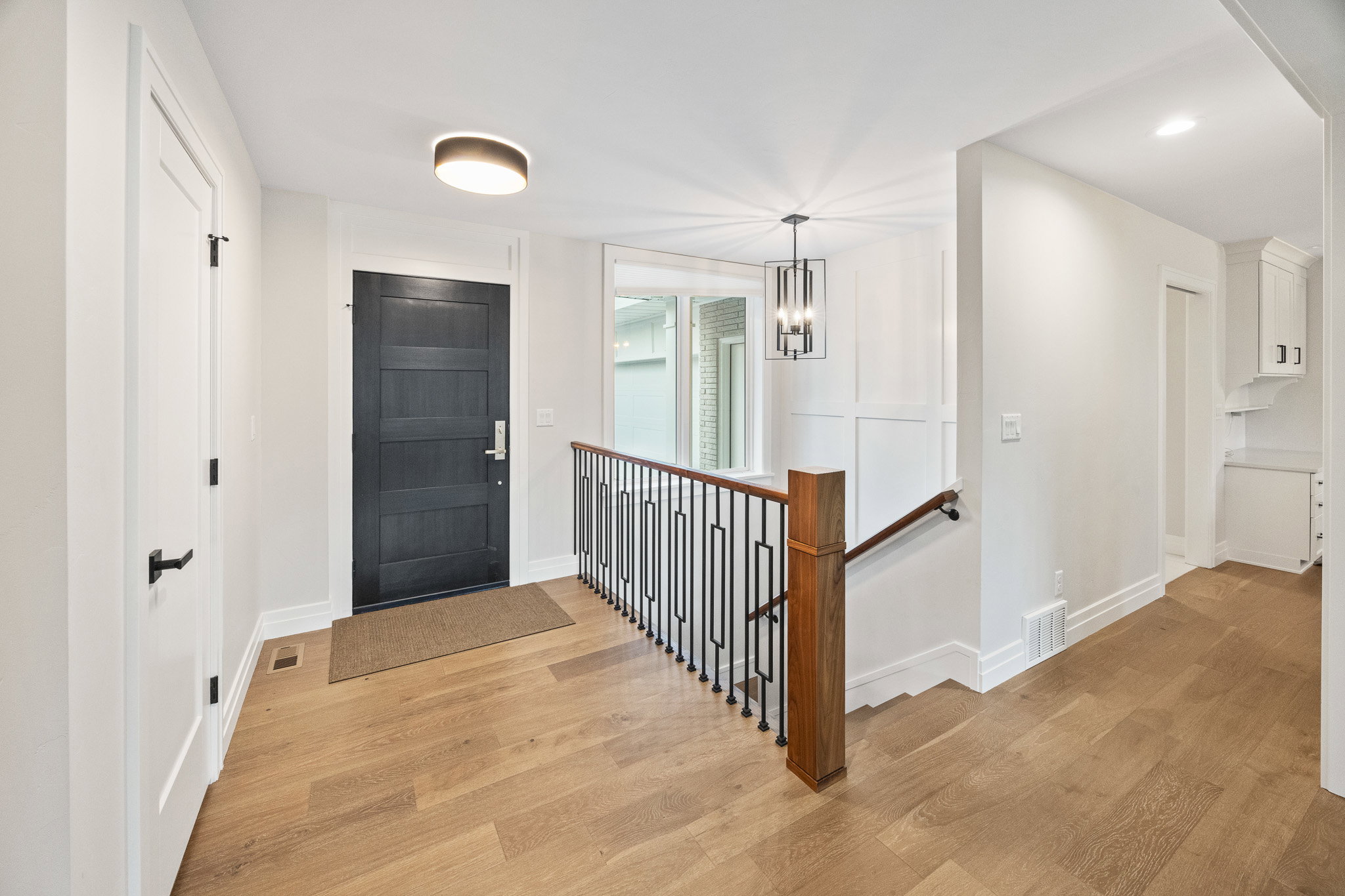 Entryway featuring wood-finish flooring, a dark paneled door, and a modern ceiling light