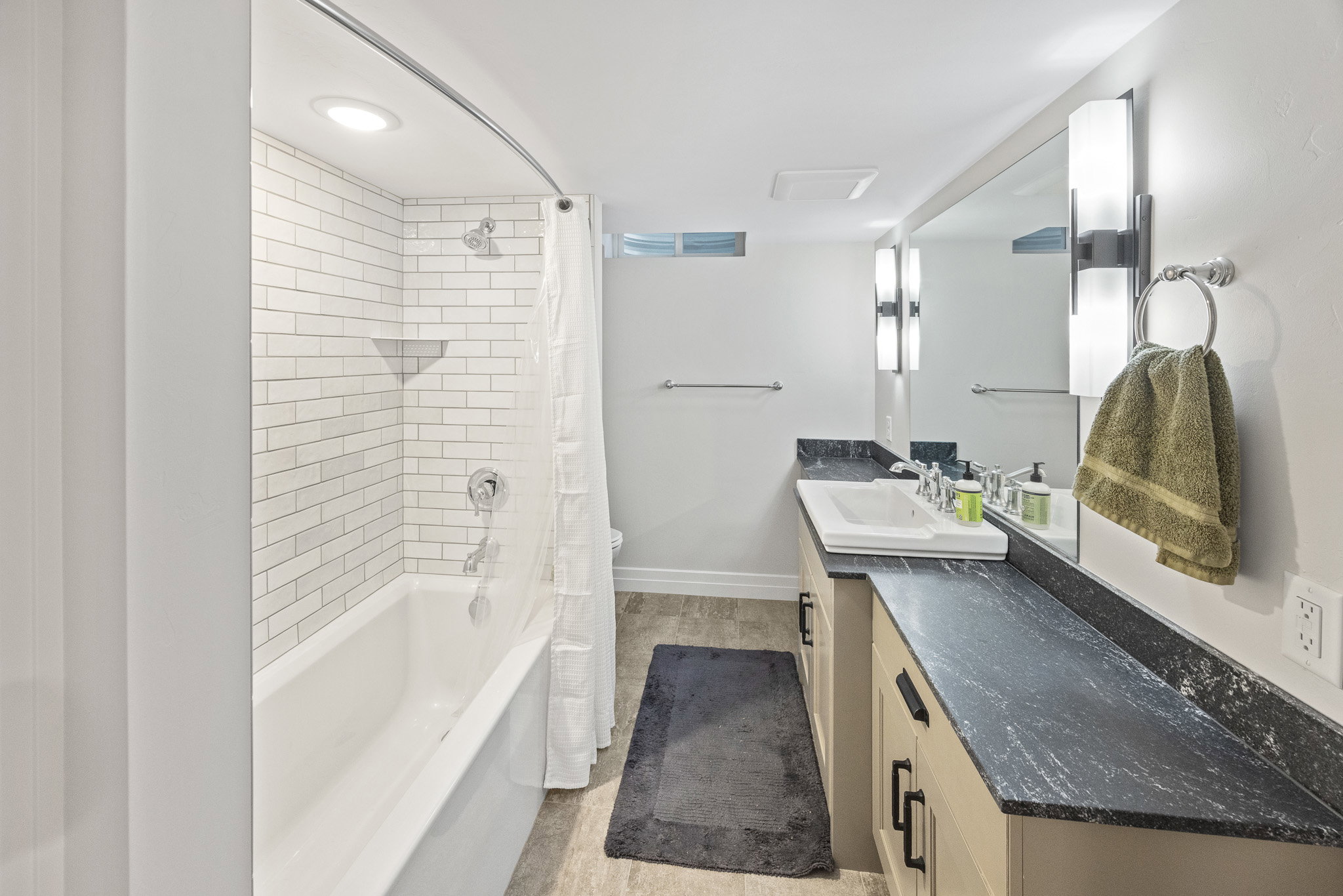 Contemporary bathroom featuring a white subway tile tub surround, recessed lighting, and a chrome shower fixture