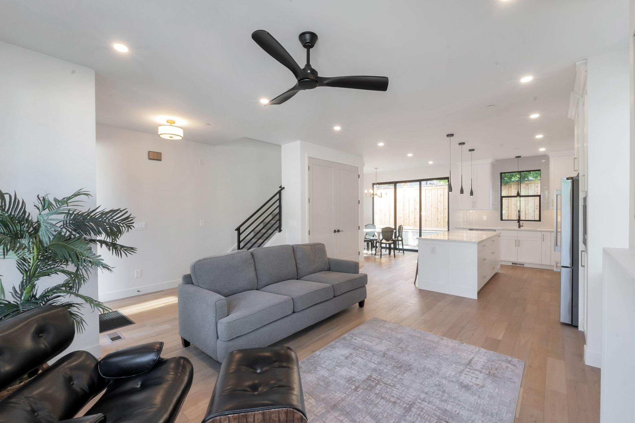 Open-concept living area featuring light wood-finish flooring, recessed lighting, and a modern ceiling fan