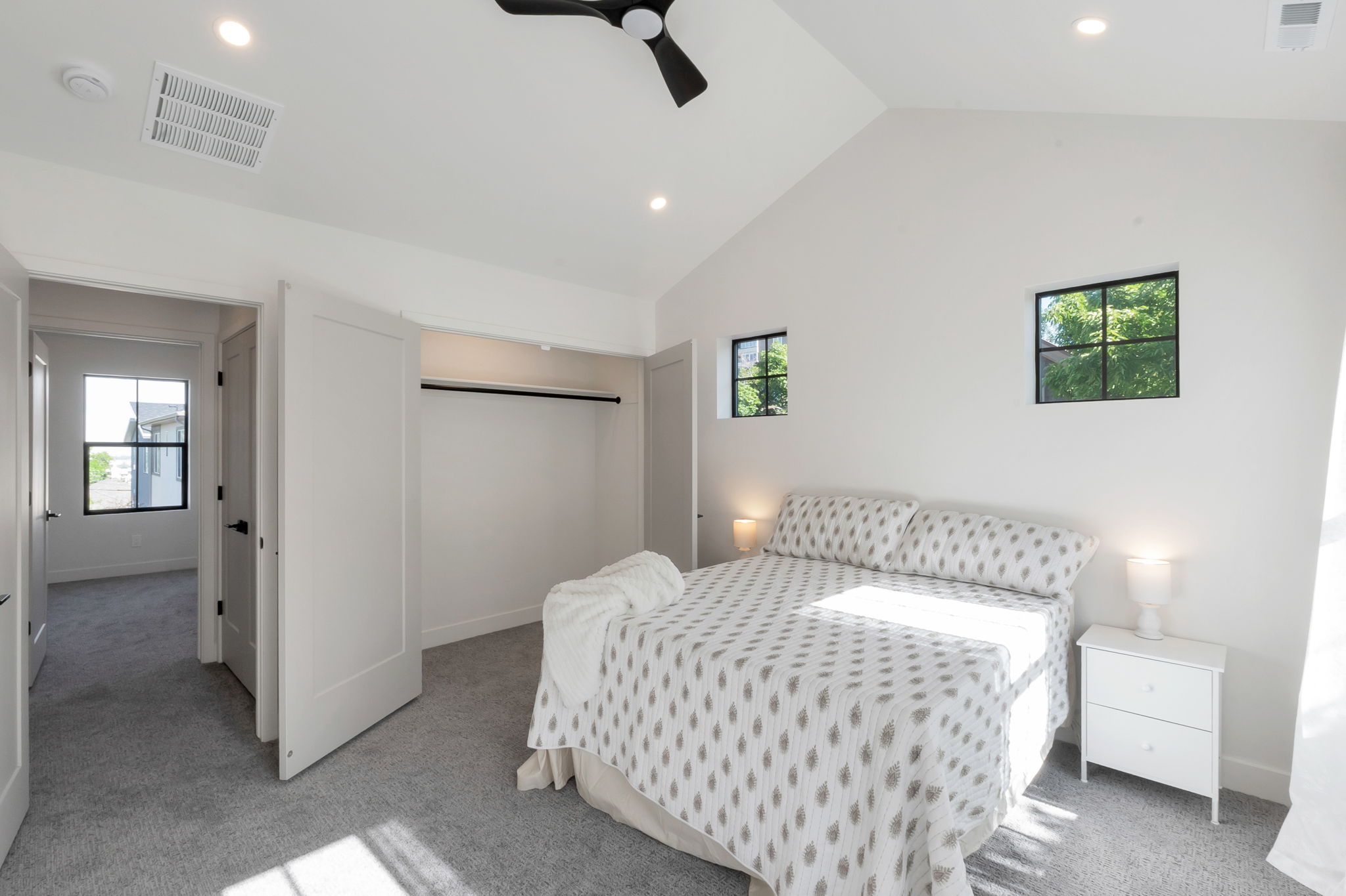 Vaulted ceiling bedroom featuring plush gray carpeting and a ceiling fan