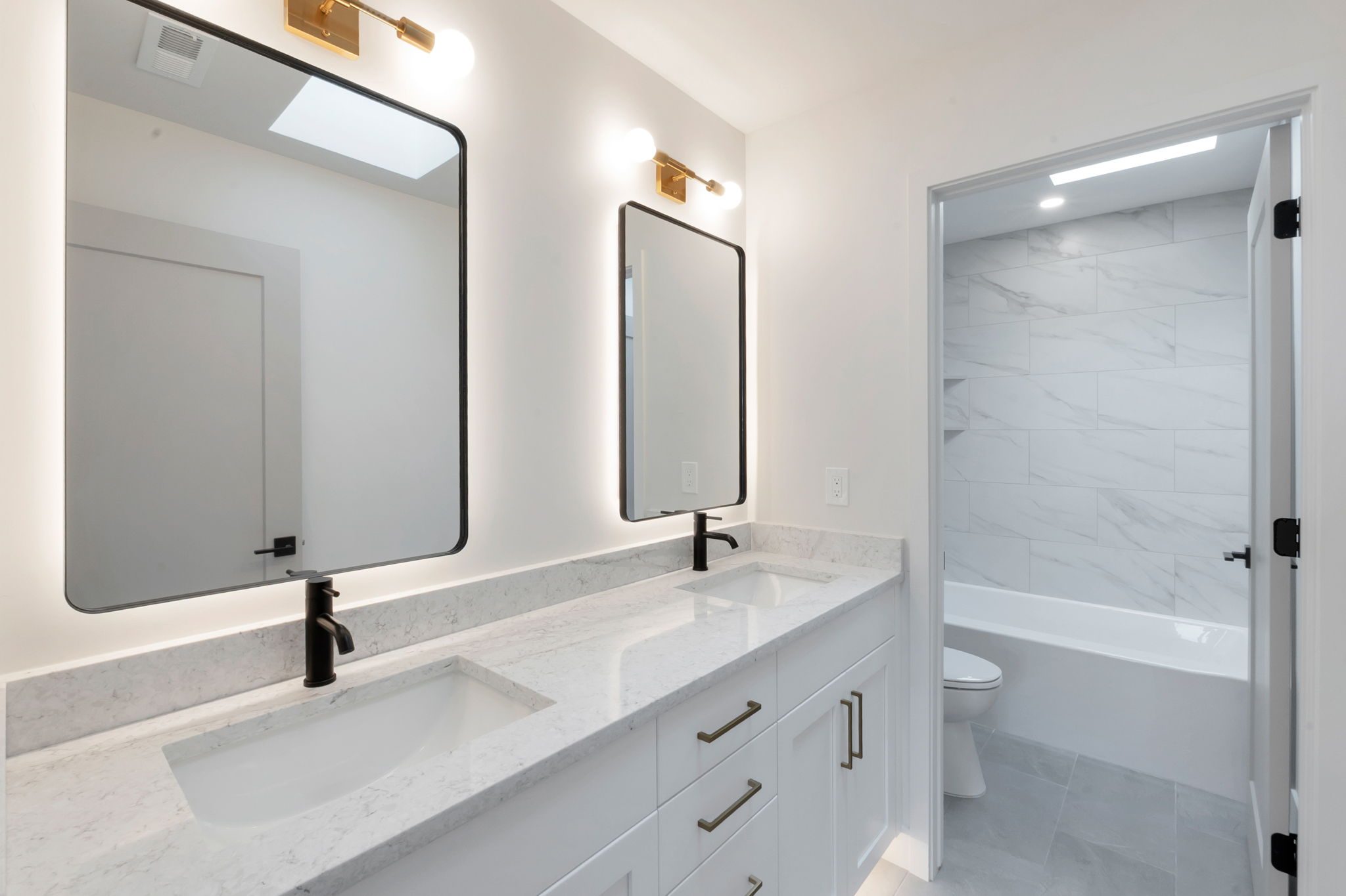 Dual vanity featuring integrated sinks, light-toned countertops, and matte black faucets