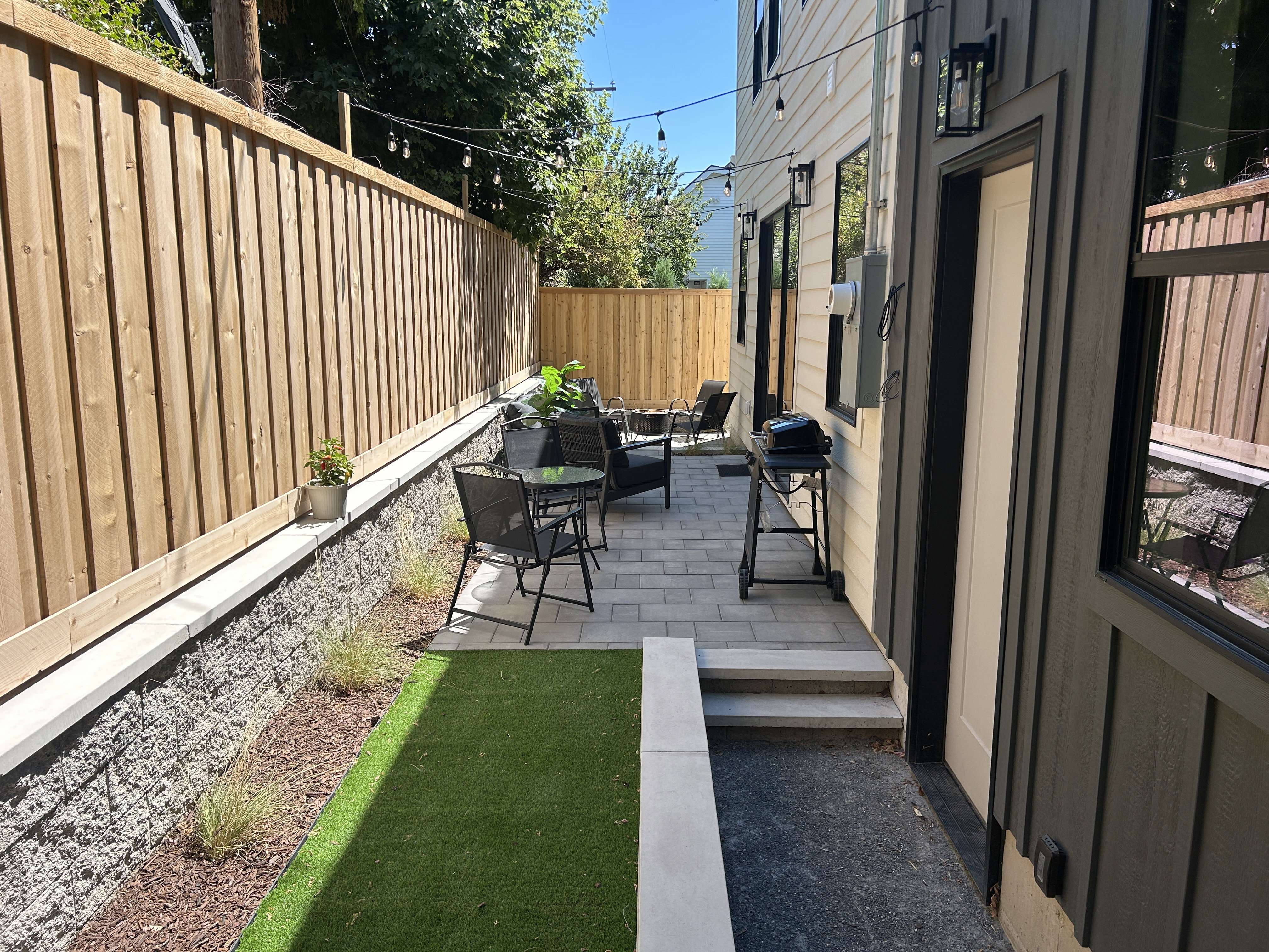 Paved patio area featuring composite fencing and an artificial turf section