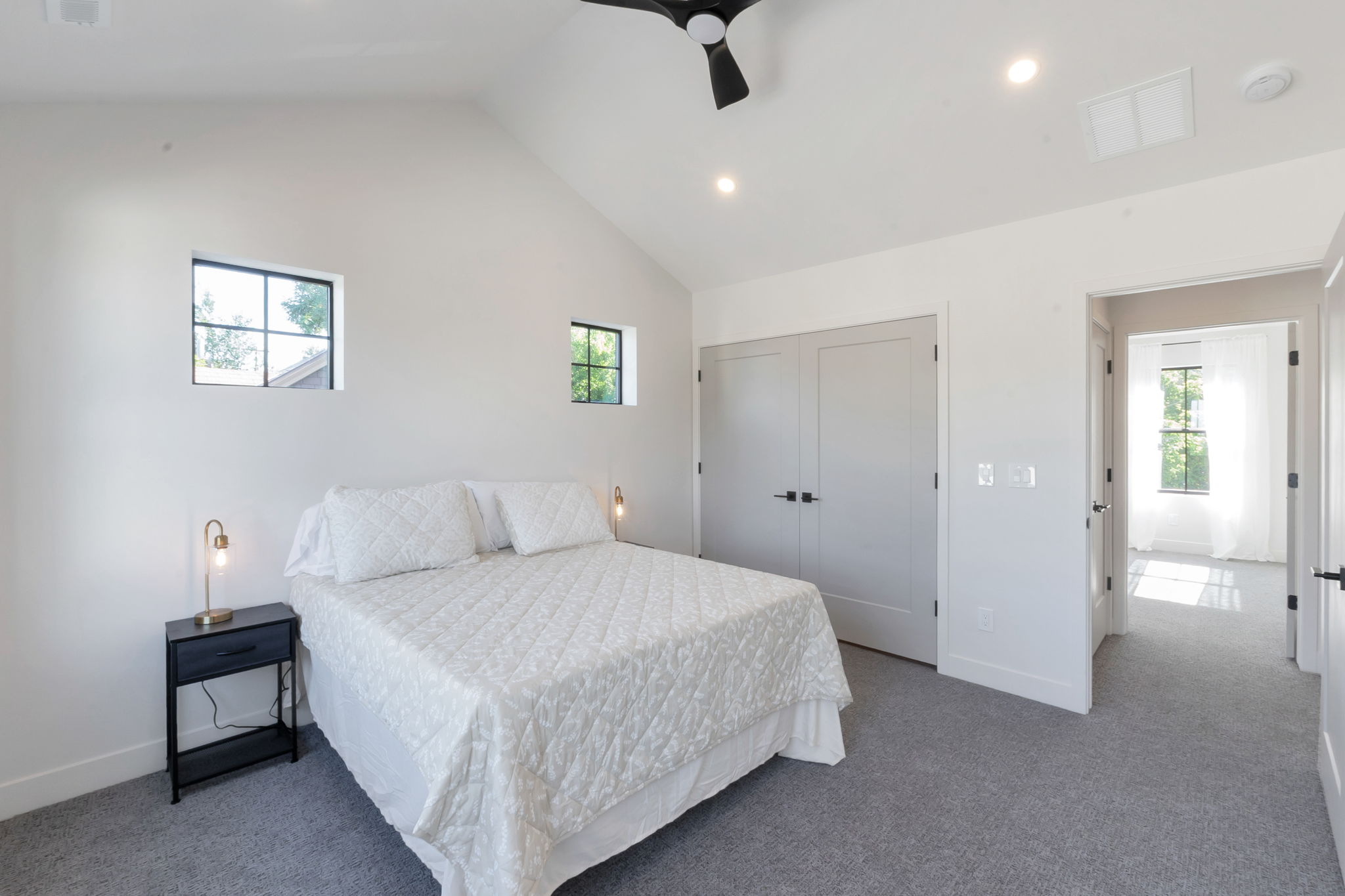 Vaulted ceiling bedroom featuring two square windows, recessed lighting, and a ceiling fan