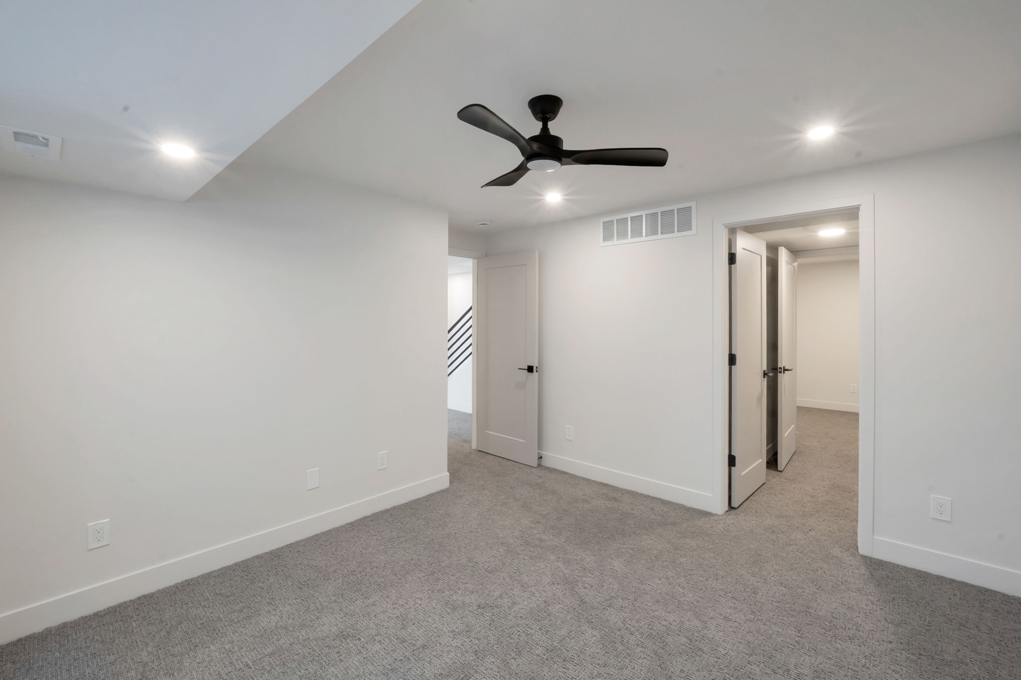 Carpeted room featuring a matte black ceiling fan, recessed lighting, white trim, and two panel doors with black hardware