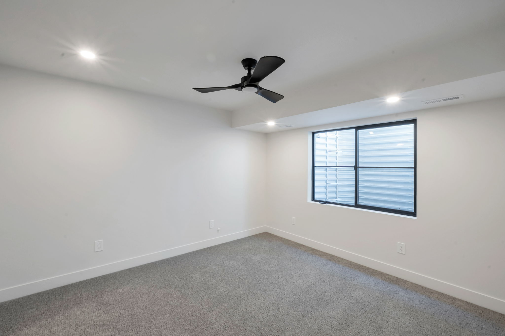 Spacious room featuring a large egress window, recessed lighting, and a contemporary ceiling fan