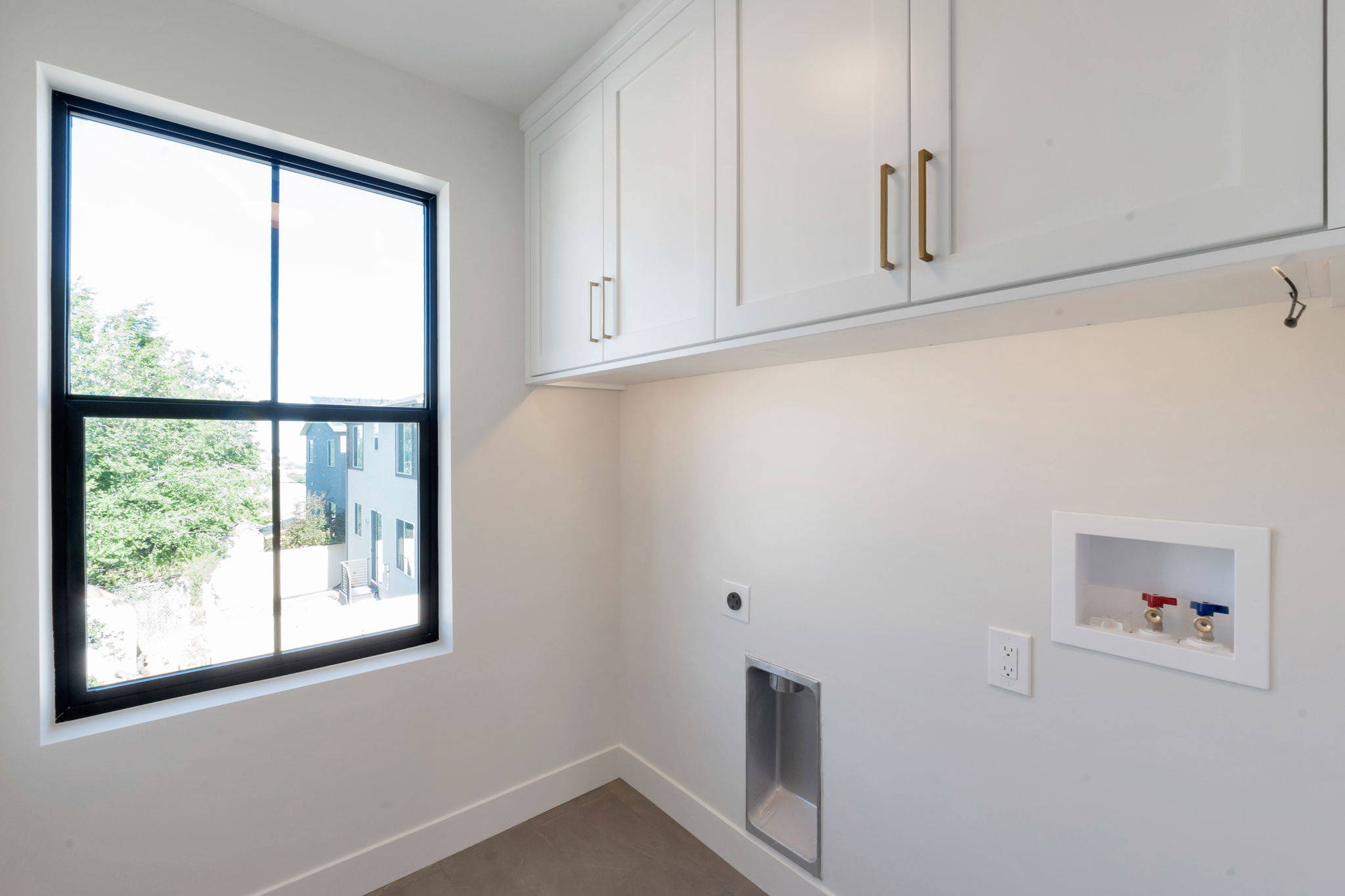 Utility area featuring shaker-style cabinetry with gold-toned hardware, under-cabinet lighting, and a large black-framed window