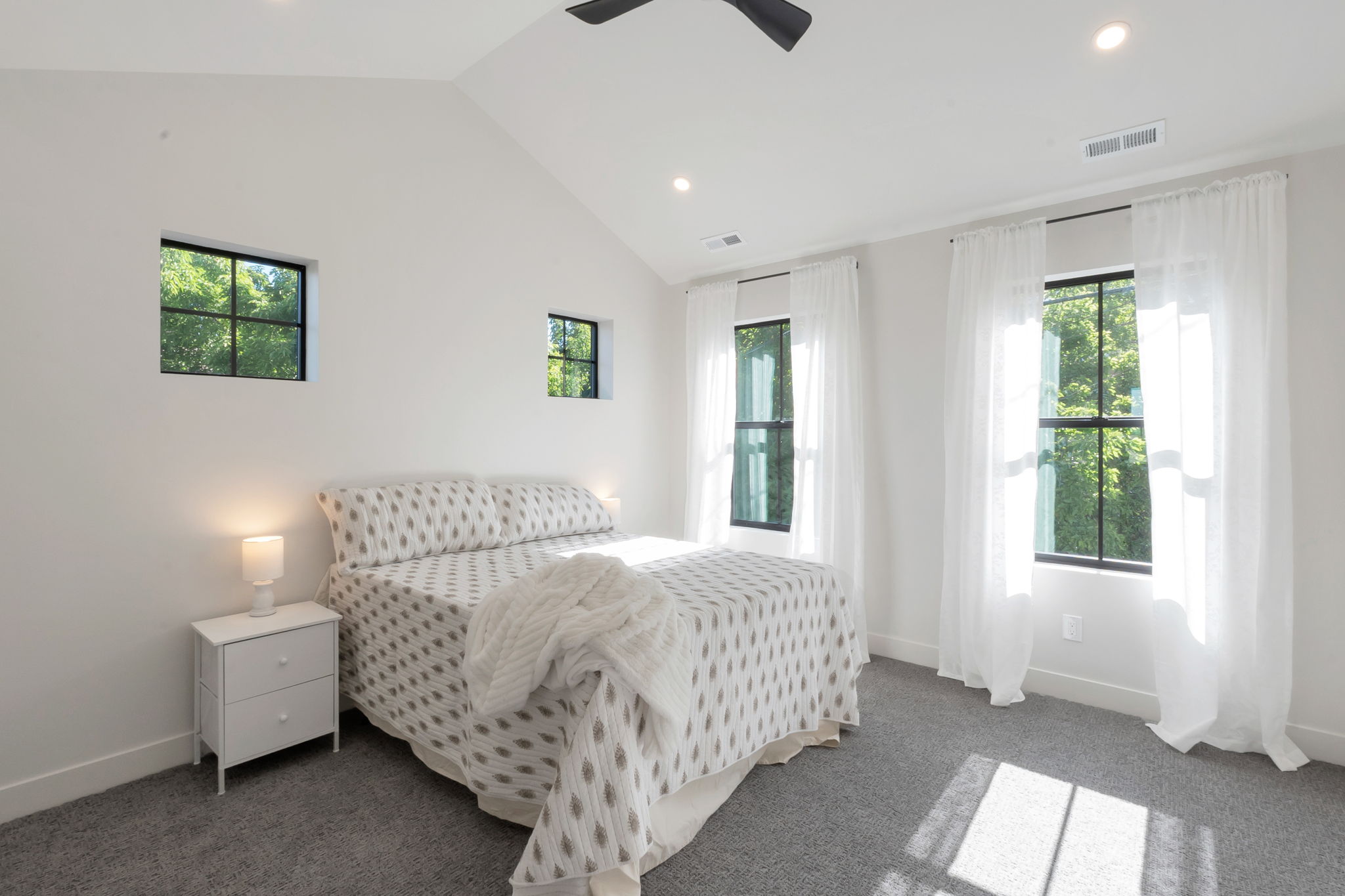 Vaulted ceiling room featuring multiple black-framed windows, recessed lighting, and a ceiling fan