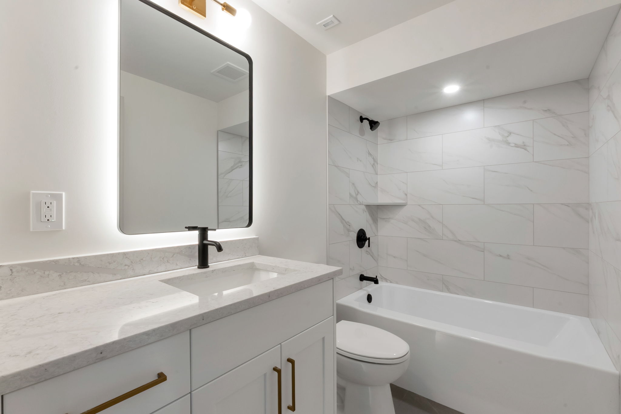 Modern bathroom featuring a single vanity with a quartz countertop, integrated sink, and matte black faucet