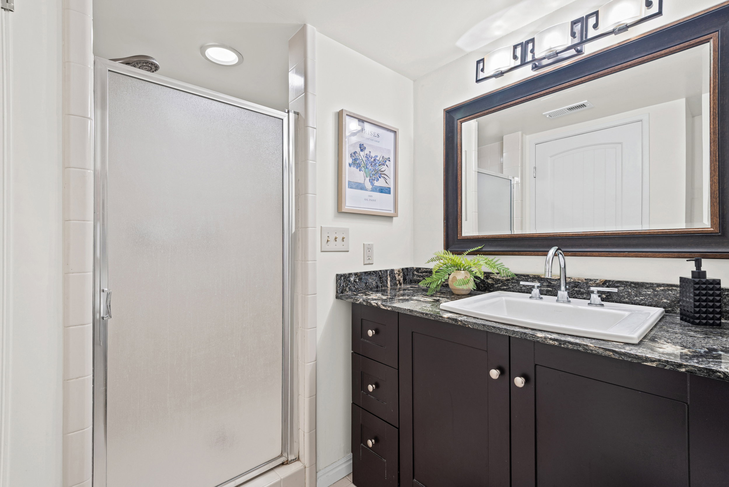 Bathroom featuring a dark wood-finish vanity with a granite countertop, undermount sink, and chrome fixtures