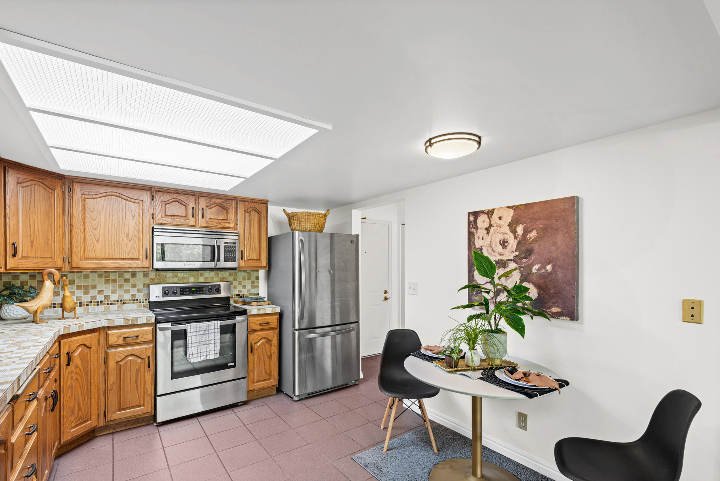 Kitchen featuring wood cabinetry, stainless steel appliances, and a skylight