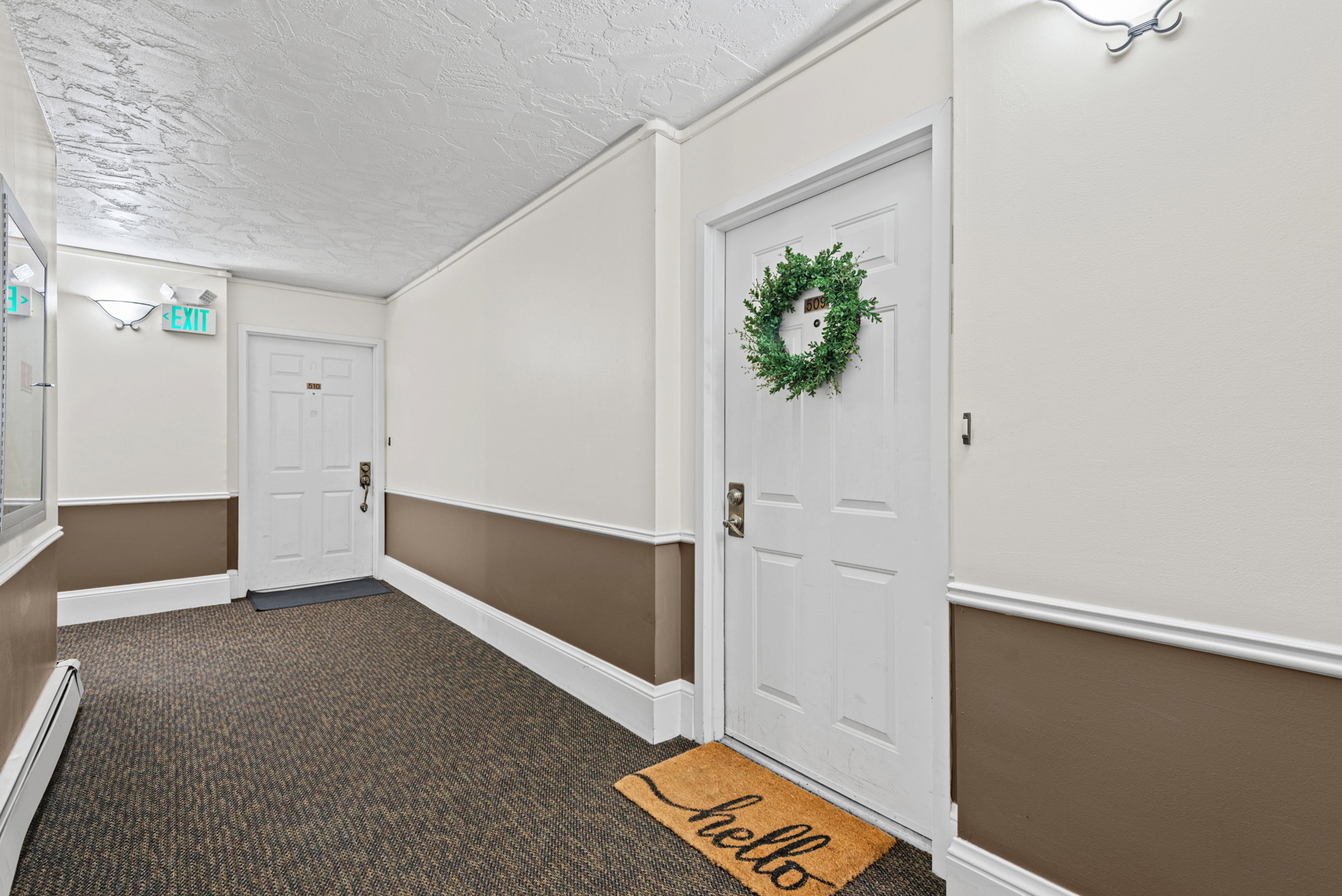 Corridor featuring textured ceiling, wall sconces, patterned carpet, and chair rail molding