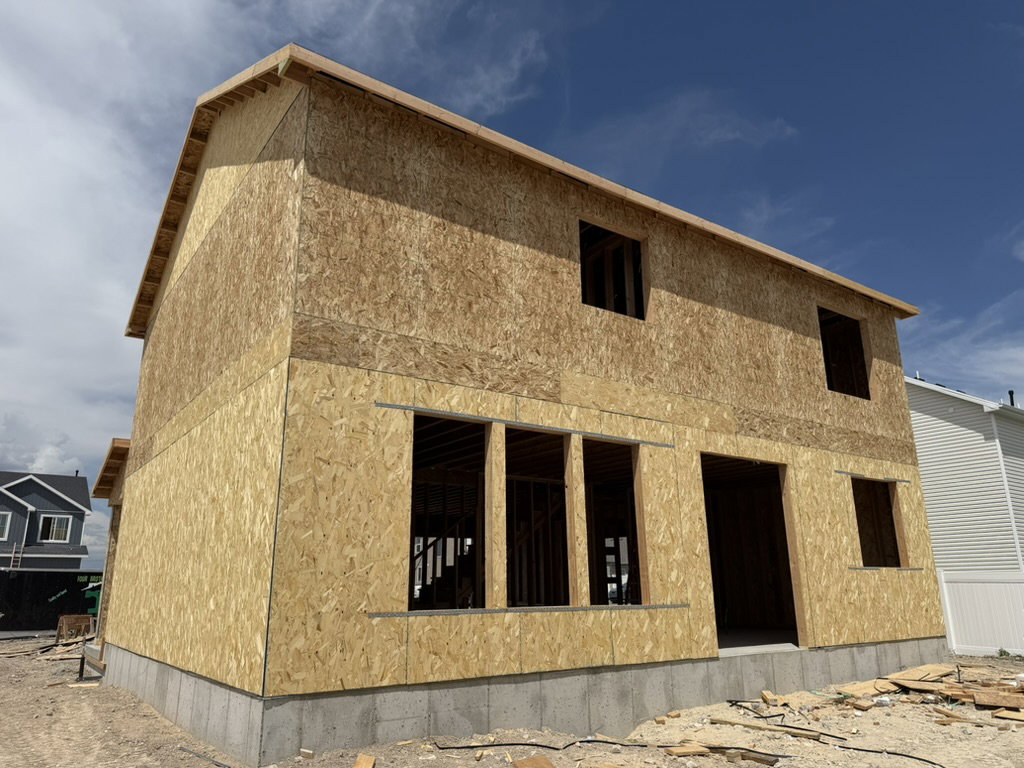 Two-story residential structure featuring OSB sheathing, a concrete block foundation, and framed window openings