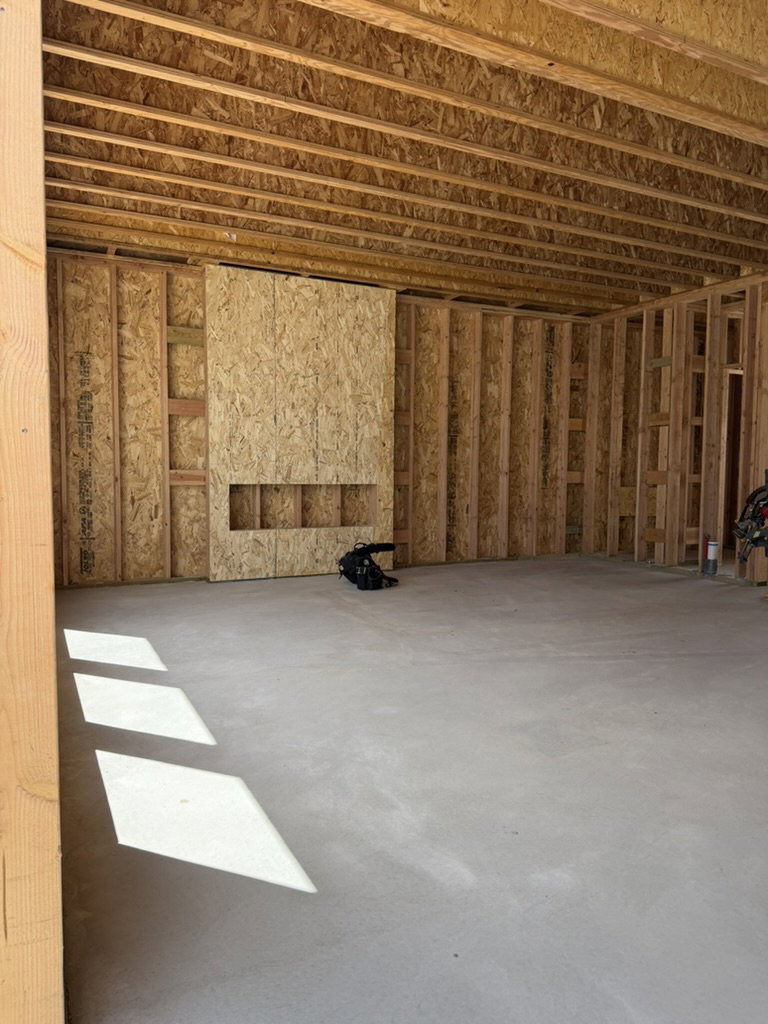 Unfinished interior space featuring exposed wood framing, an open ceiling with visible joists, and a concrete slab floor