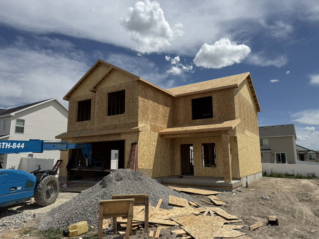 Two-story residence under construction with a multi-gabled roofline and an integrated garage space