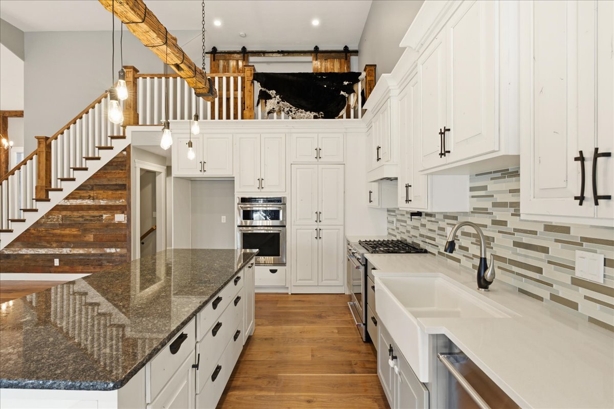 Gourmet kitchen featuring white cabinetry, integrated appliances, and an expansive island with a polished countertop
