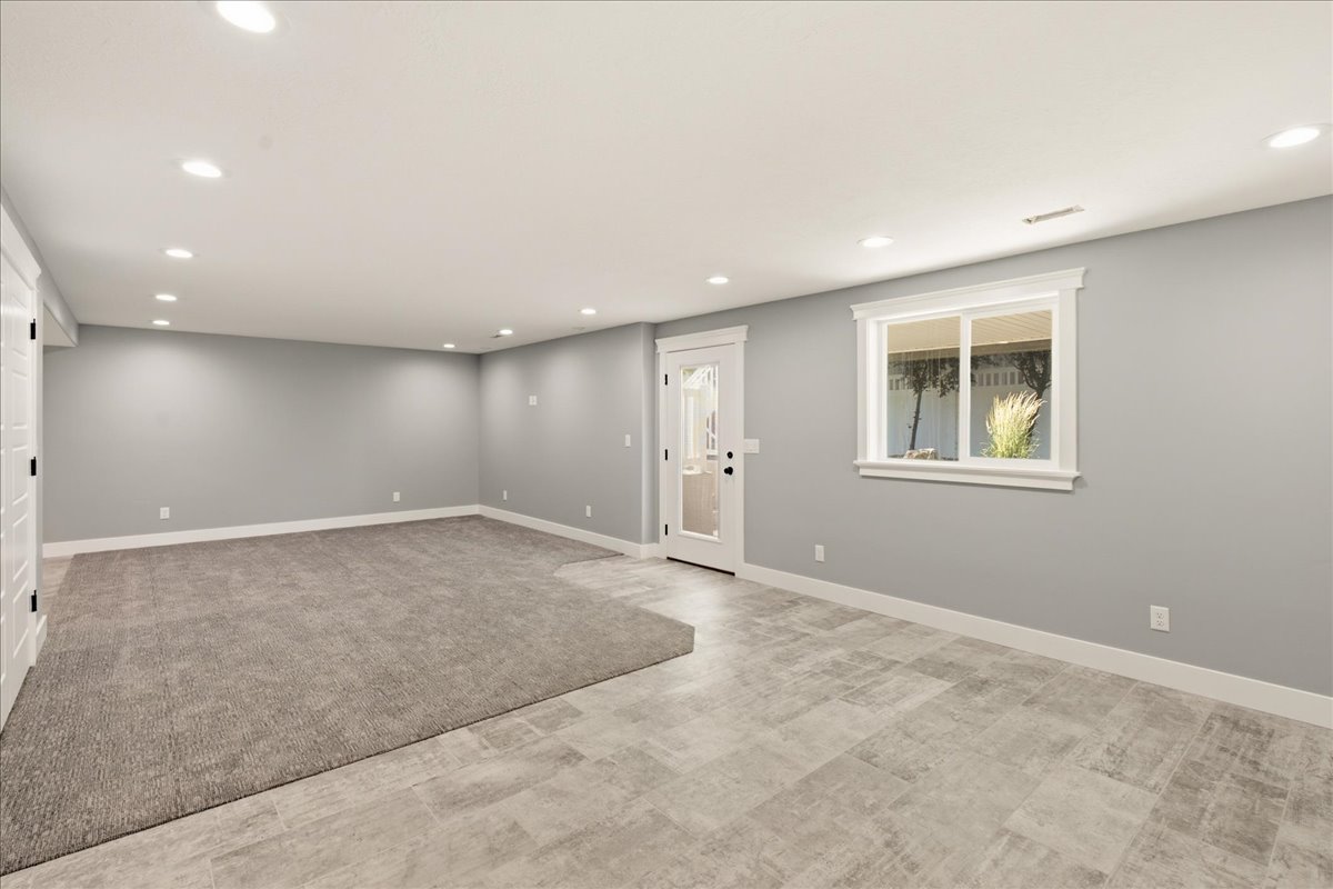 Spacious room featuring recessed lighting, a direct exterior access door, and a large window with white trim