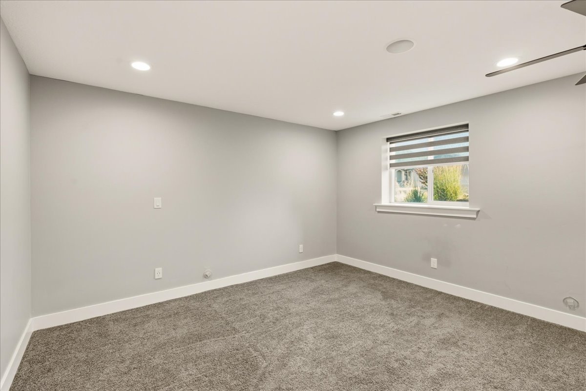 Neutral-toned room featuring light gray walls, plush gray carpeting, and white baseboards