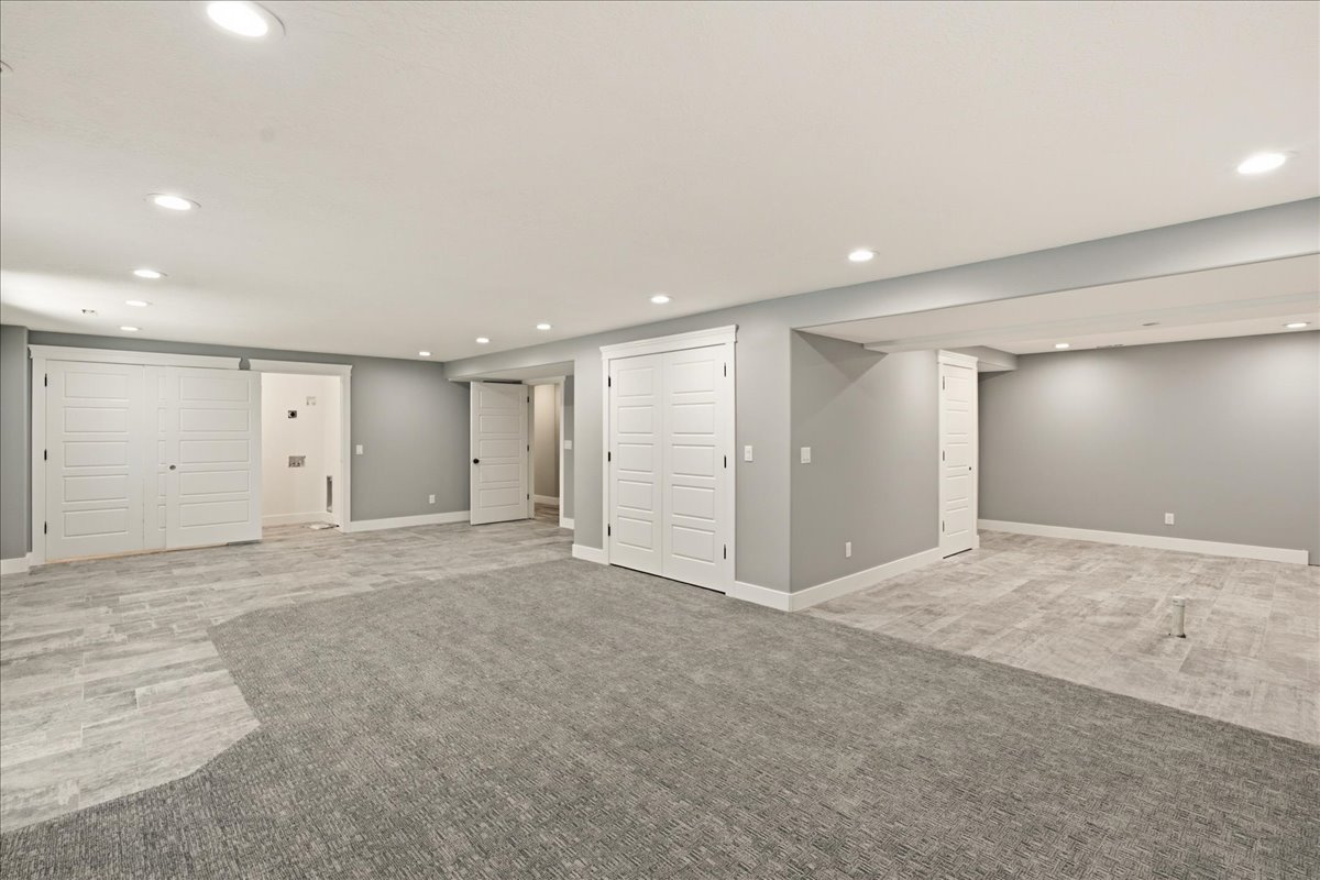 Spacious room featuring recessed lighting, a combination of tile and carpet flooring, and multiple white panel doors