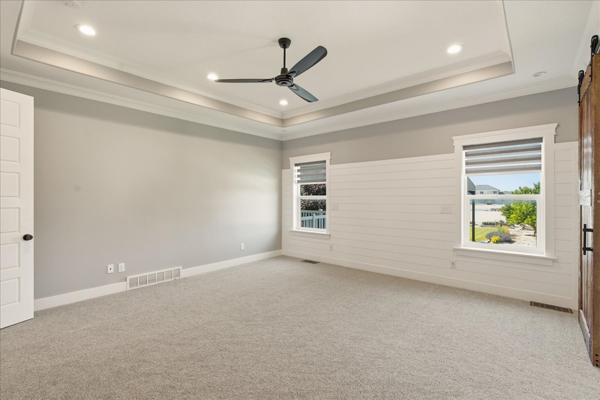 Spacious room featuring a tray ceiling with recessed lighting, a contemporary ceiling fan, and light gray wall paint