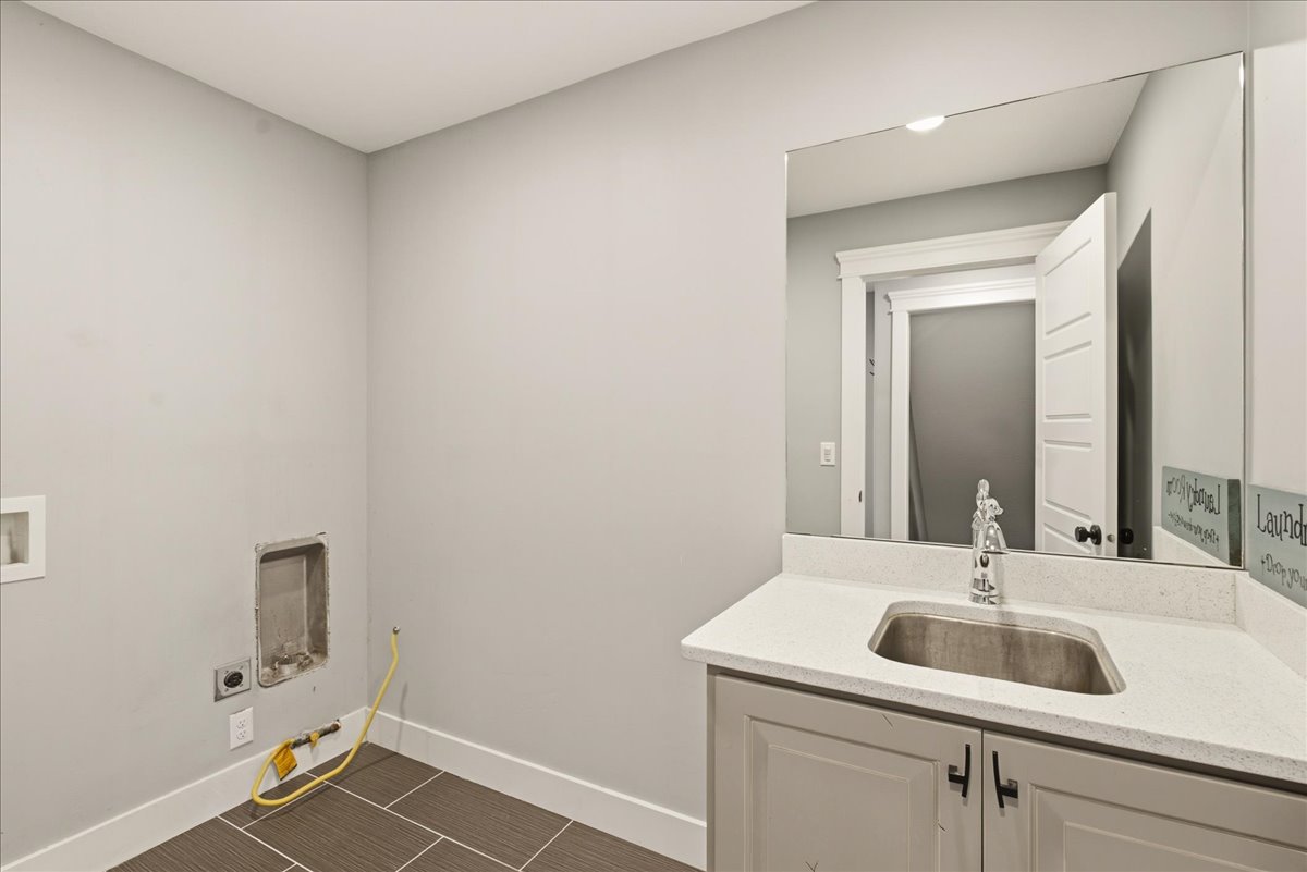Utility room featuring a light gray vanity with a stainless steel sink, a spacious countertop, and a large wall-mounted mirror
