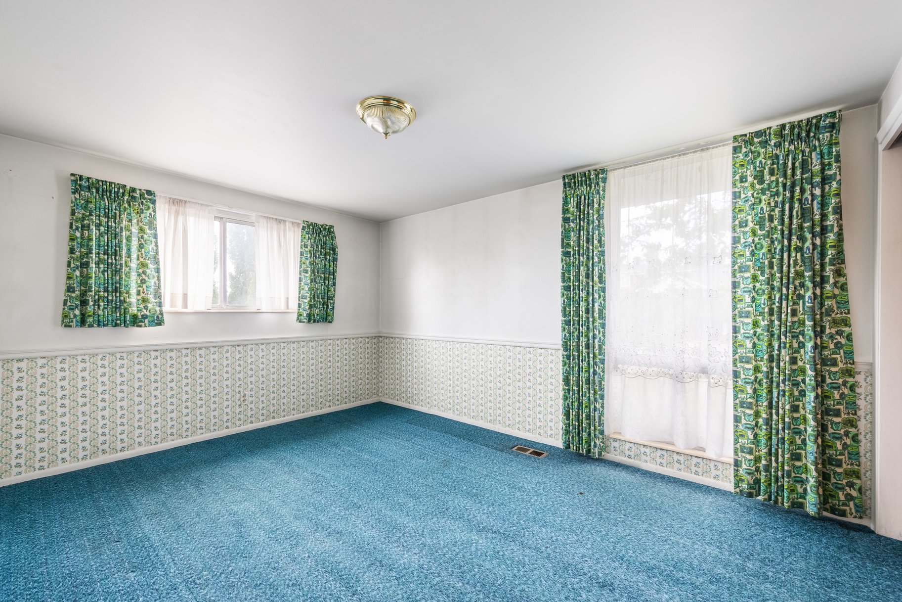 Room with blue carpeting and white walls above a patterned wallpaper border