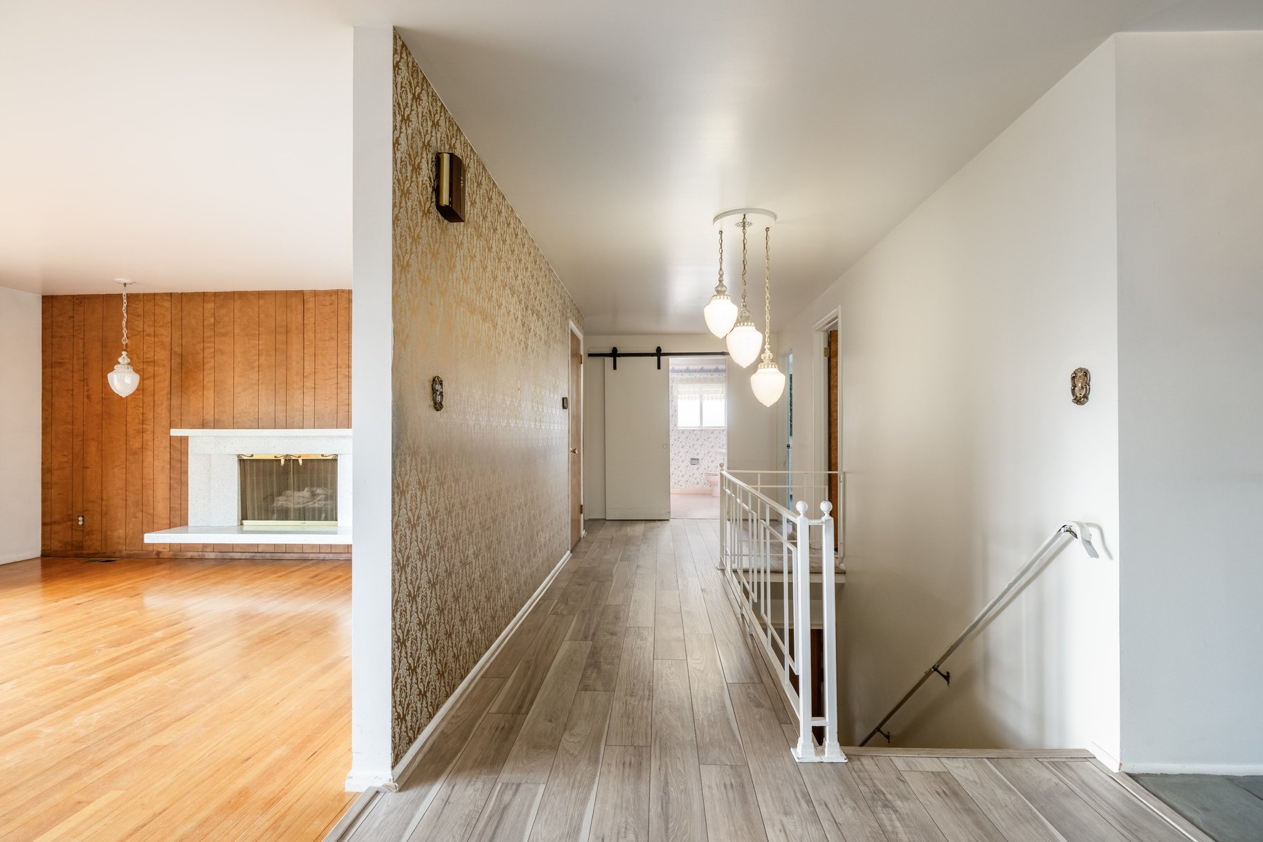 Entryway featuring wood-finish flooring, a pendant light fixture, and a white metal staircase railing