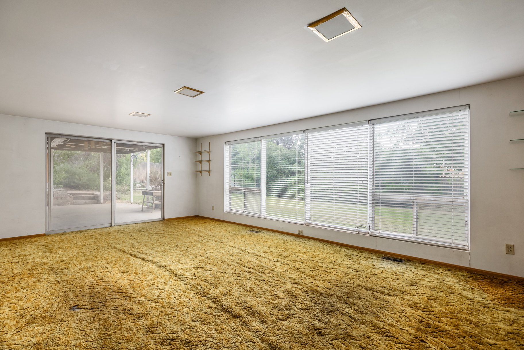 Spacious interior with full-height windows, sliding glass door, recessed lighting, and wall-mounted shelving