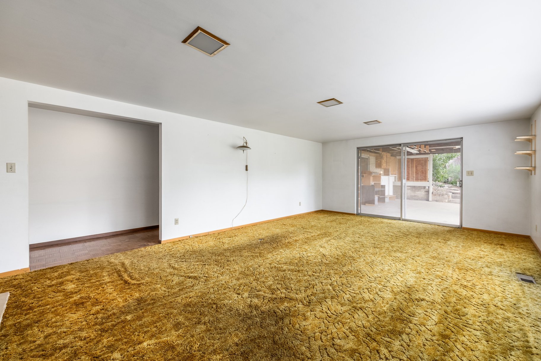 Spacious interior room with neutral white walls, plush carpeting, and recessed ceiling lights
