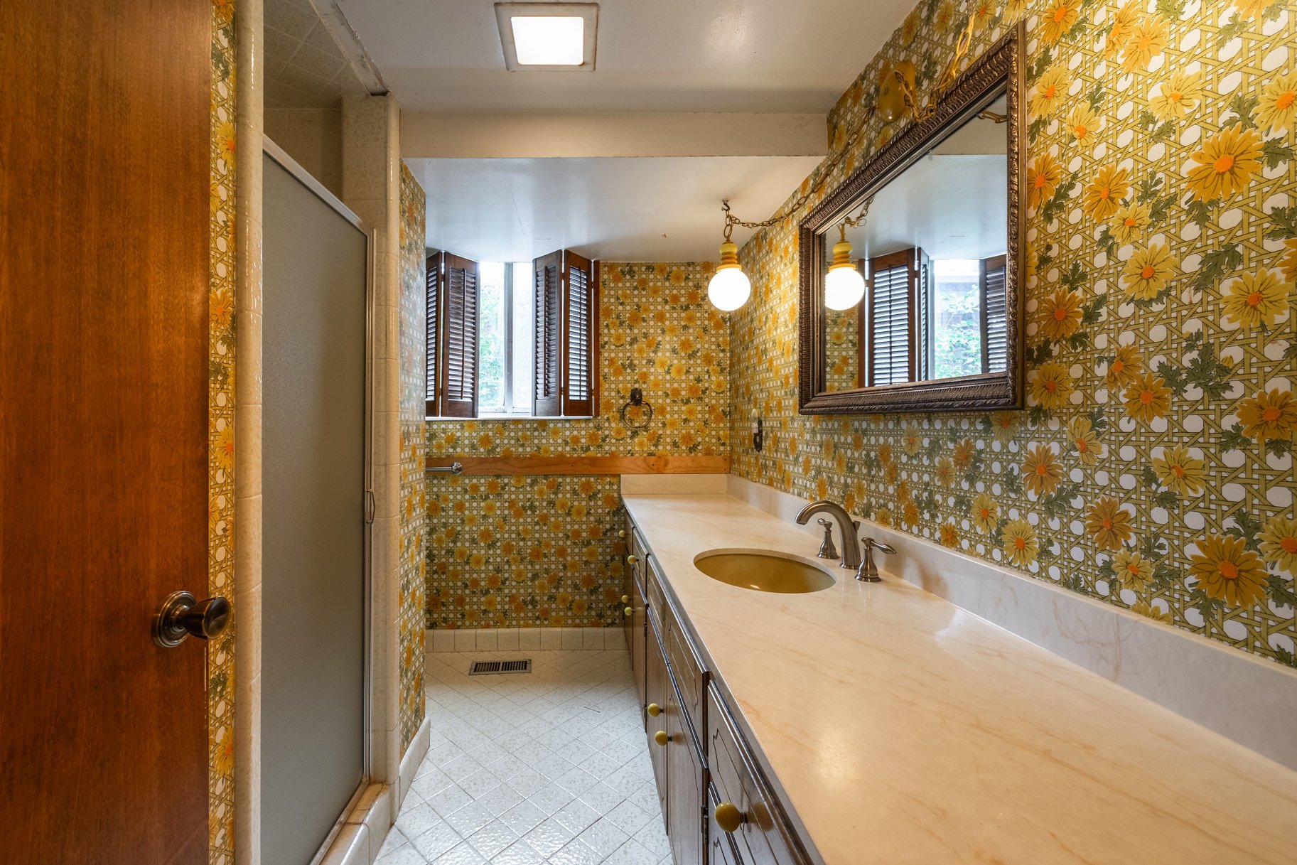 Bathroom featuring a glass-enclosed shower, a vanity with a light-toned countertop, a single basin sink, and wood-finish cabinetry