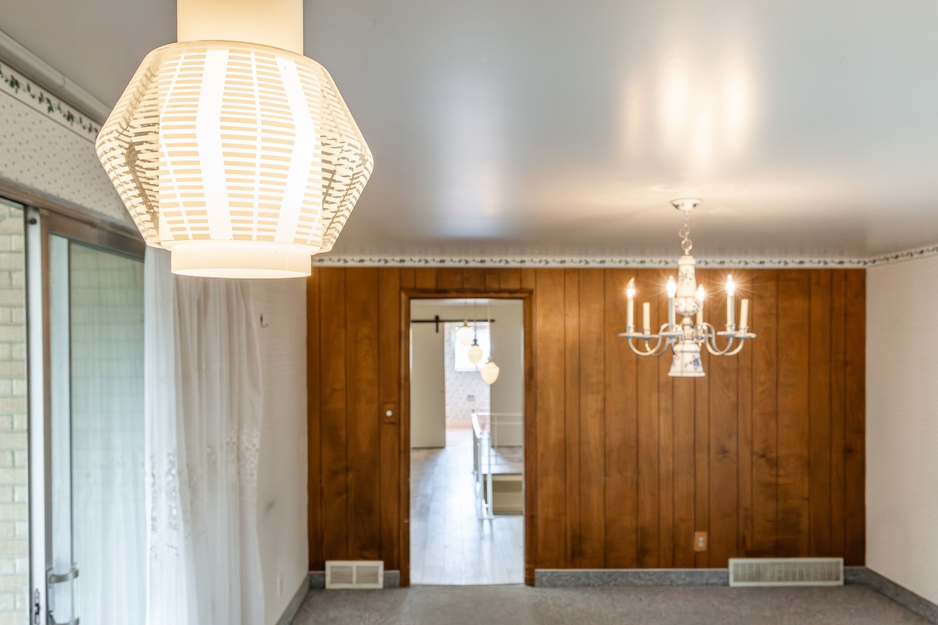 Interior space featuring a paneled accent wall, a multi-arm chandelier, and a decorative pendant light