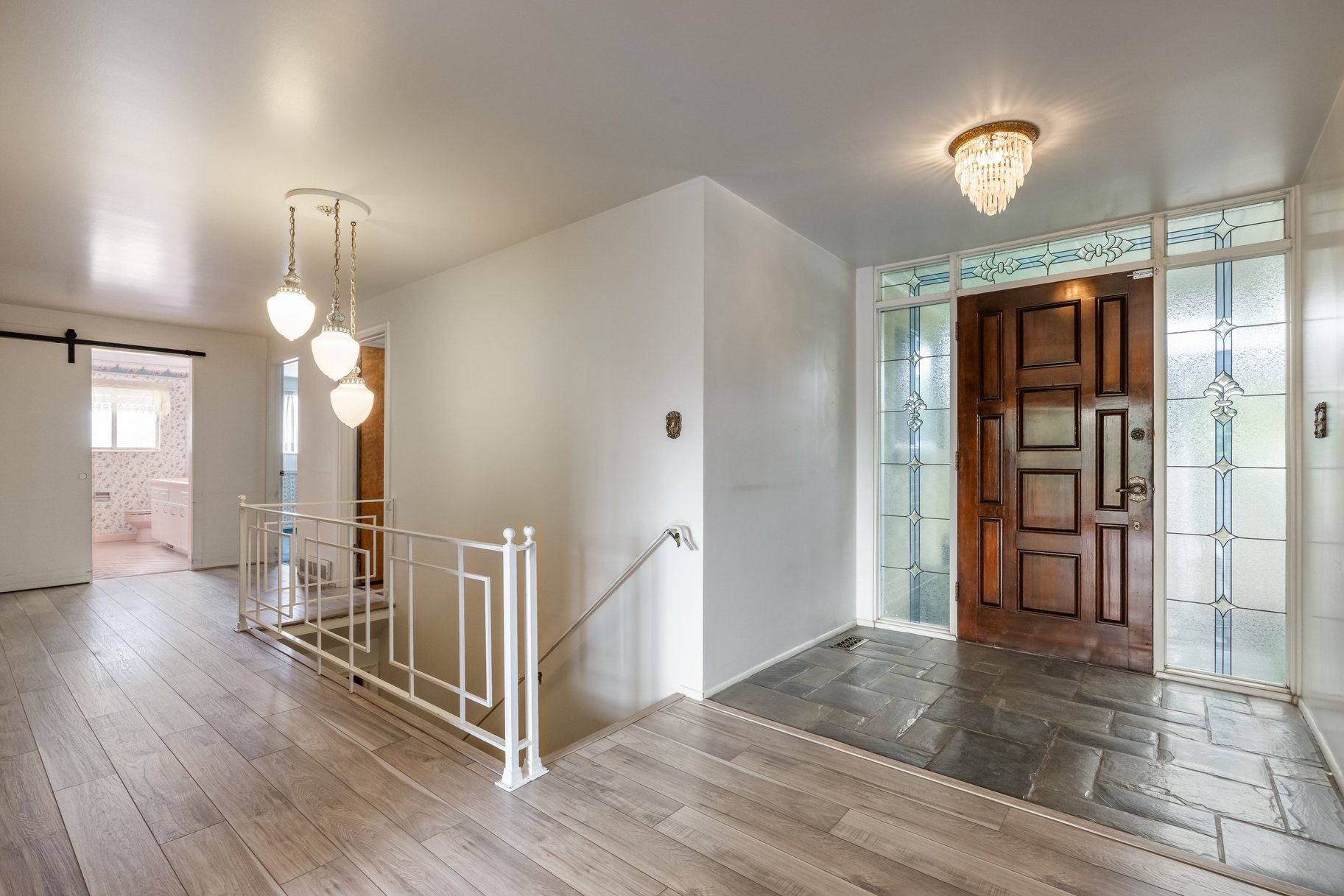 Entryway featuring a rich wood panel door with intricate stained-glass sidelights and transom
