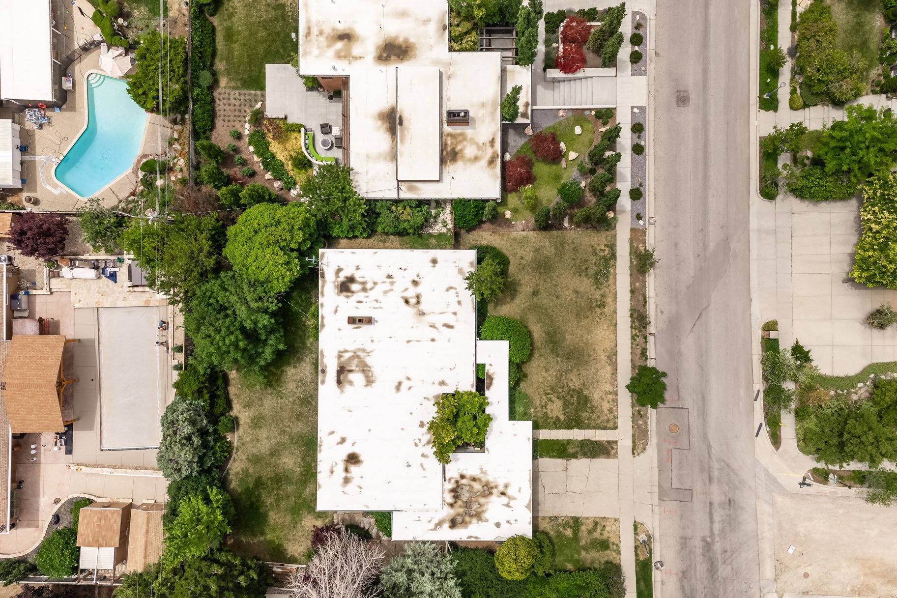 Property lot featuring a rectangular shape, mature landscaping on one side, and a sidewalk border