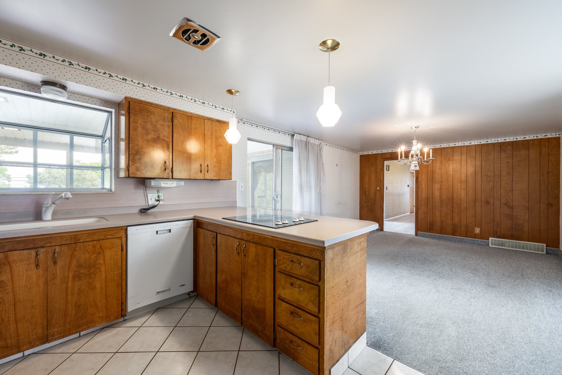 Kitchen featuring wood cabinetry, white tile flooring, and integrated cooktop