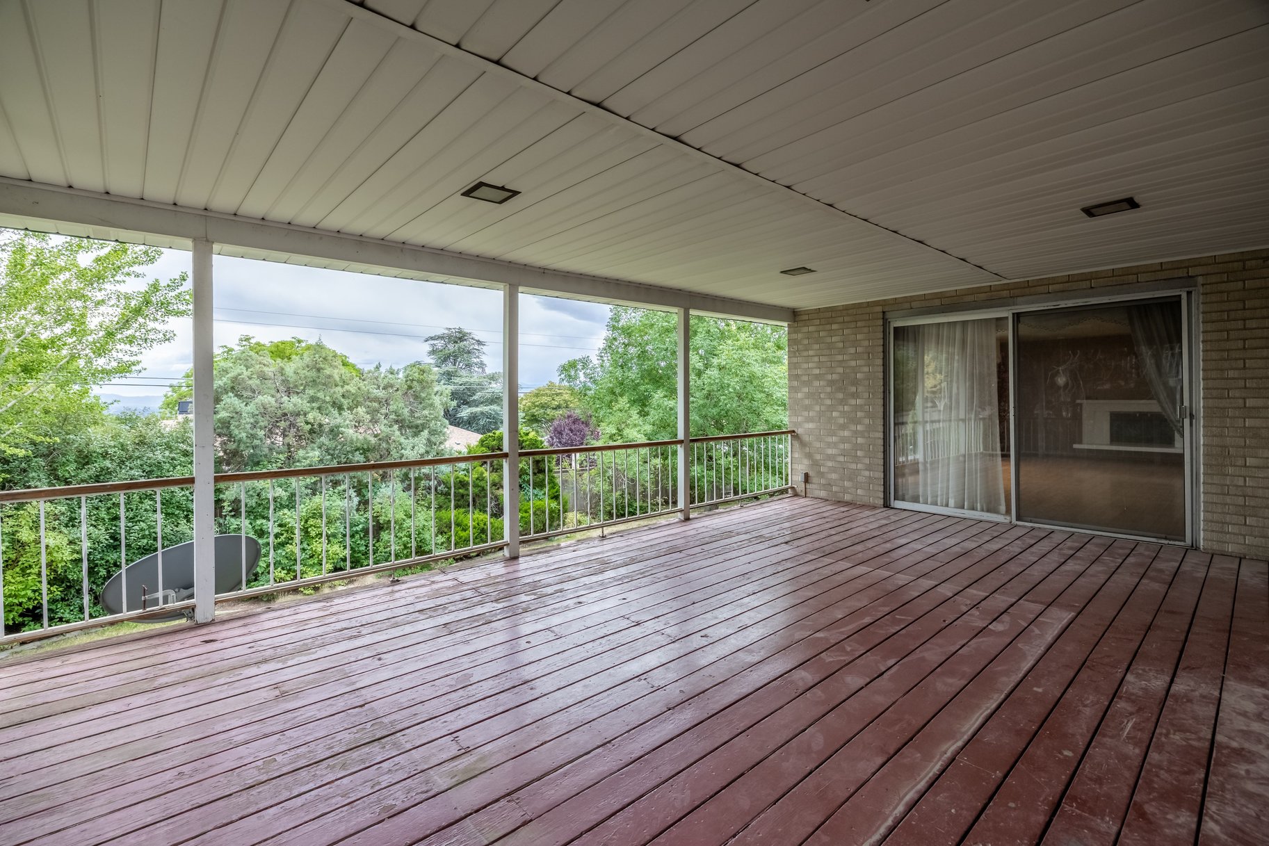 Expansive covered deck featuring wood-finish flooring and a white metal railing