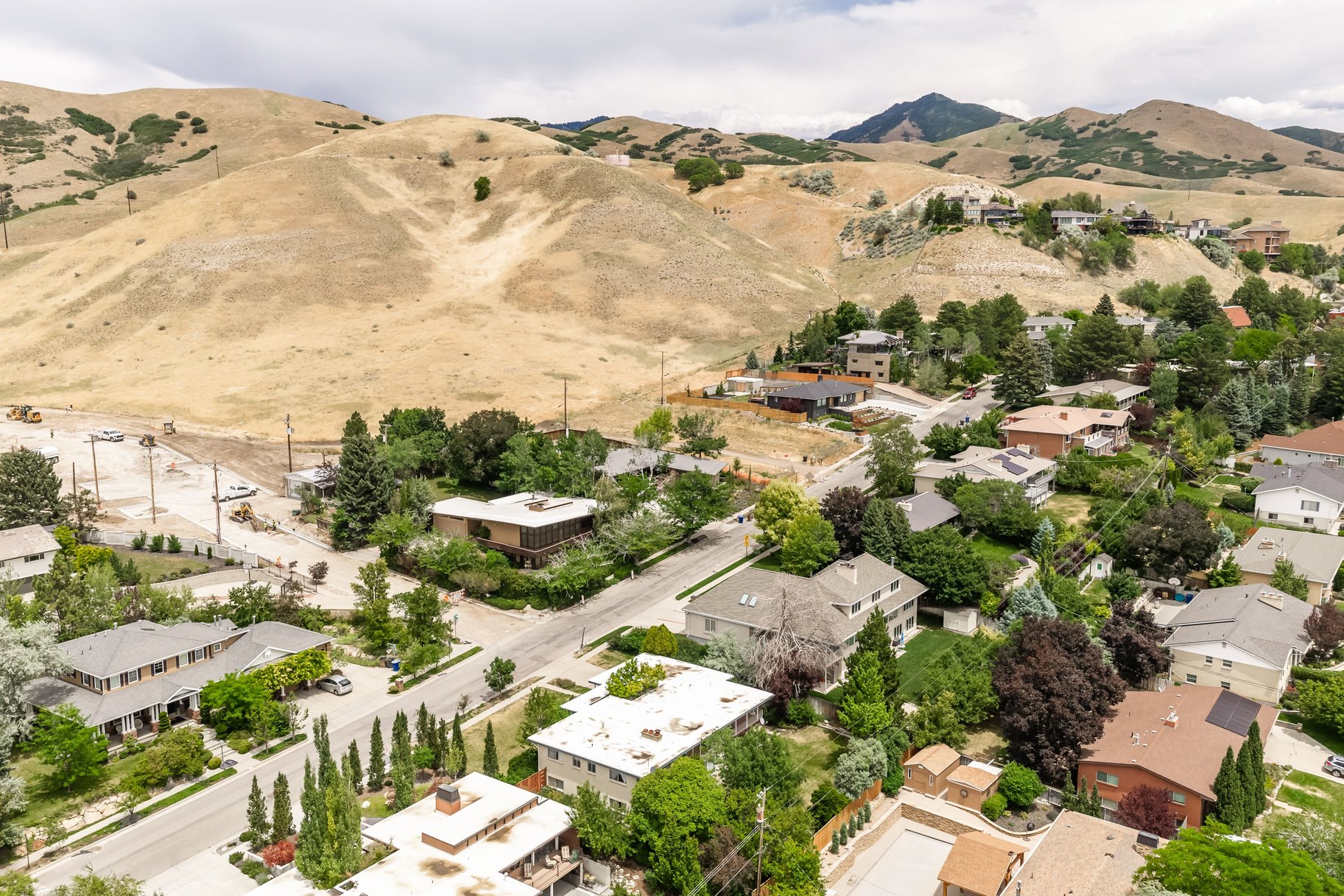 Aerial perspective showcasing residential properties nestled at the base of expansive, arid foothills