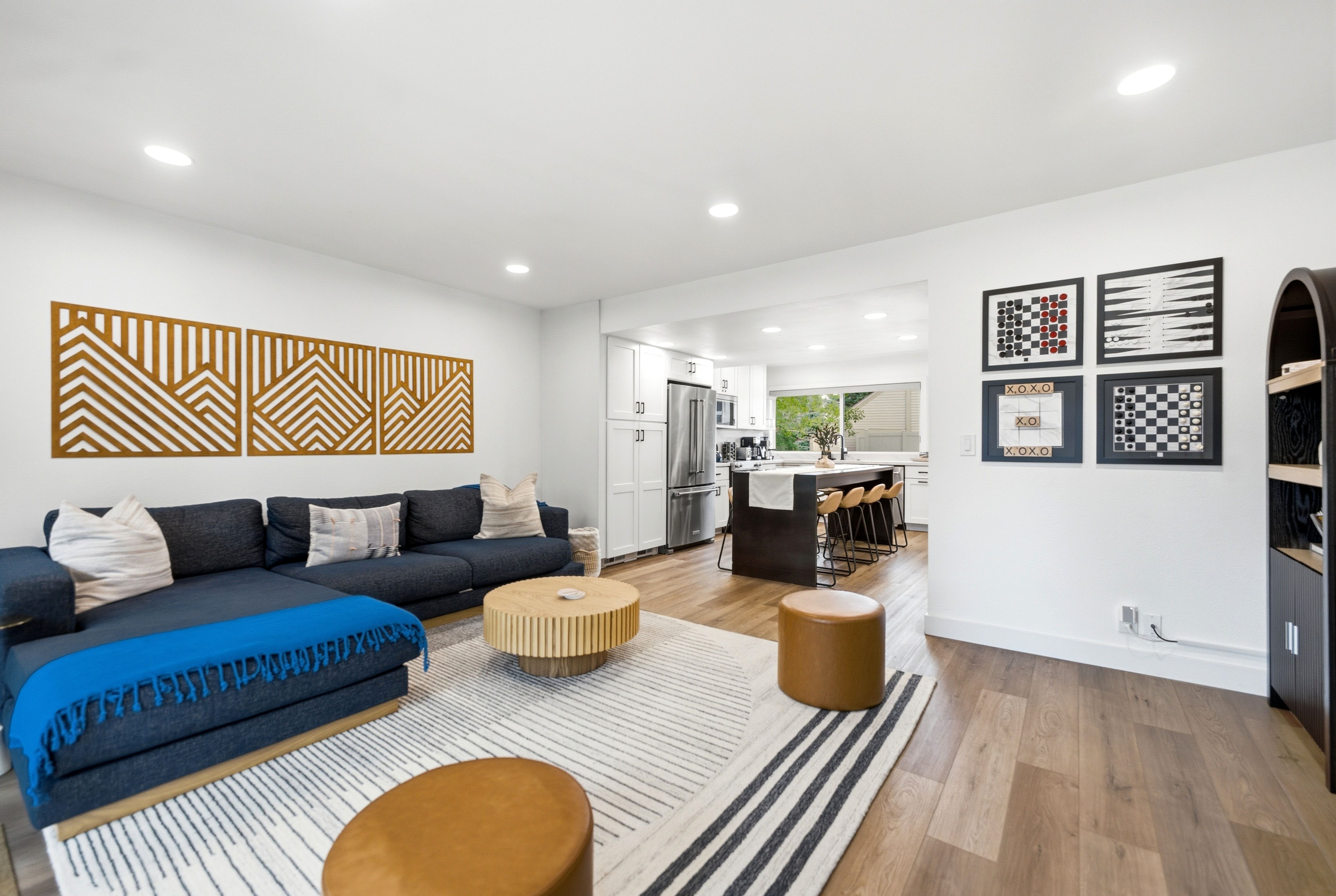 Open-concept living space featuring wood-finish flooring, recessed lighting, and a kitchen area with a central island and stainless steel appliances