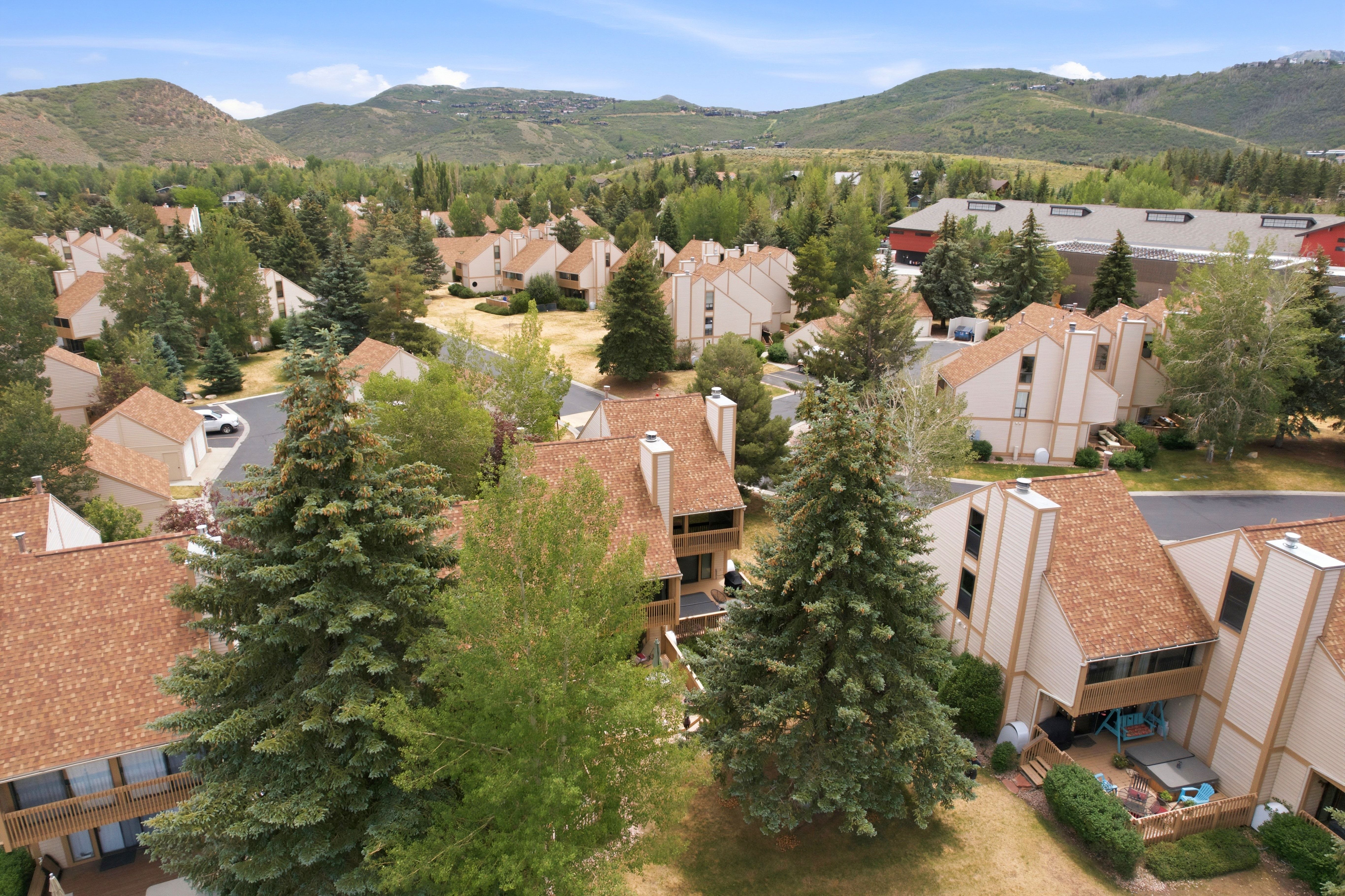 Aerial perspective showcasing a residential community with numerous multi-story townhomes, each featuring a pitched shingle roof and light-toned siding