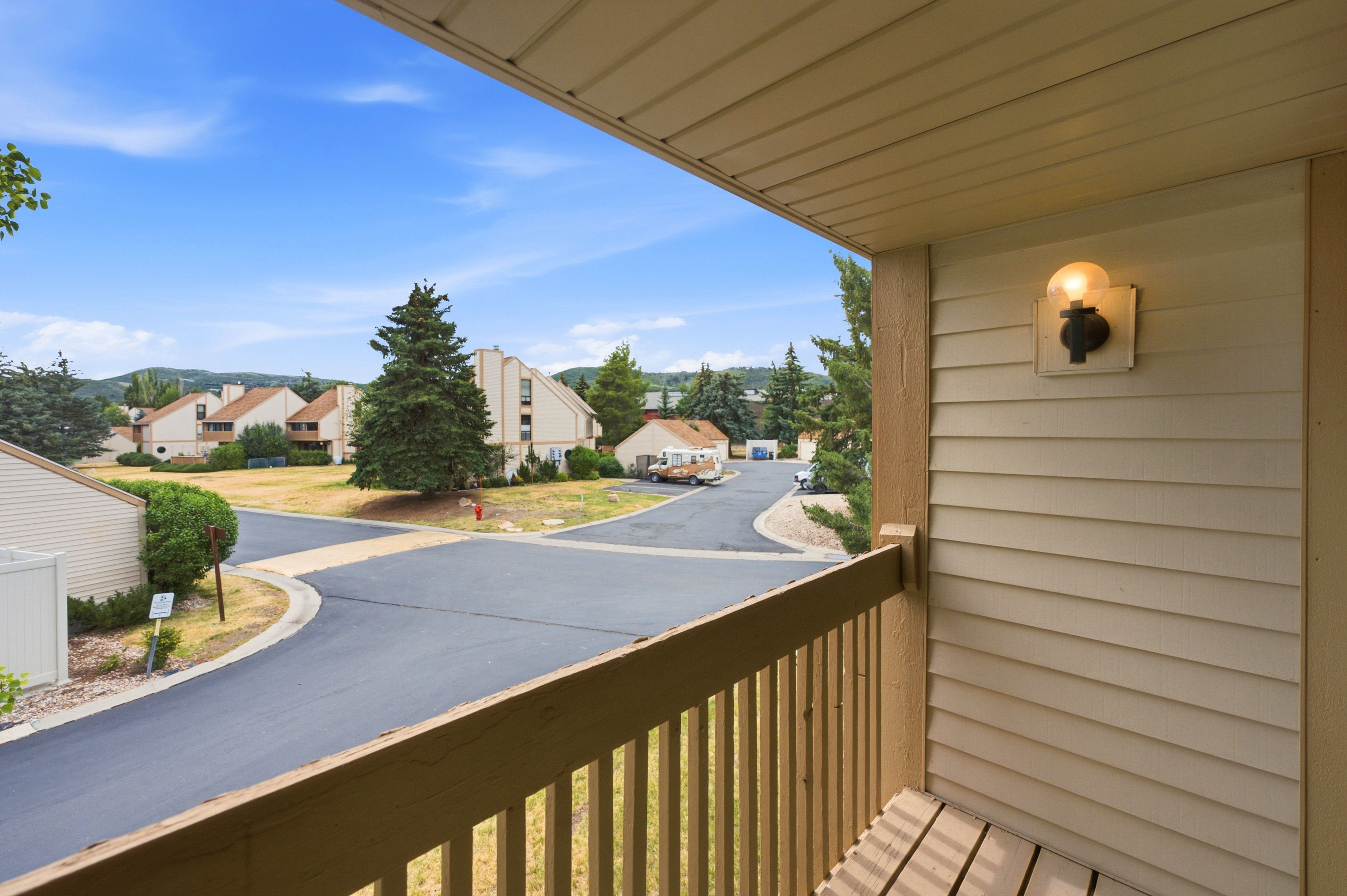 Private balcony featuring slatted wood flooring, a simple wall-mounted light fixture, and horizontal siding