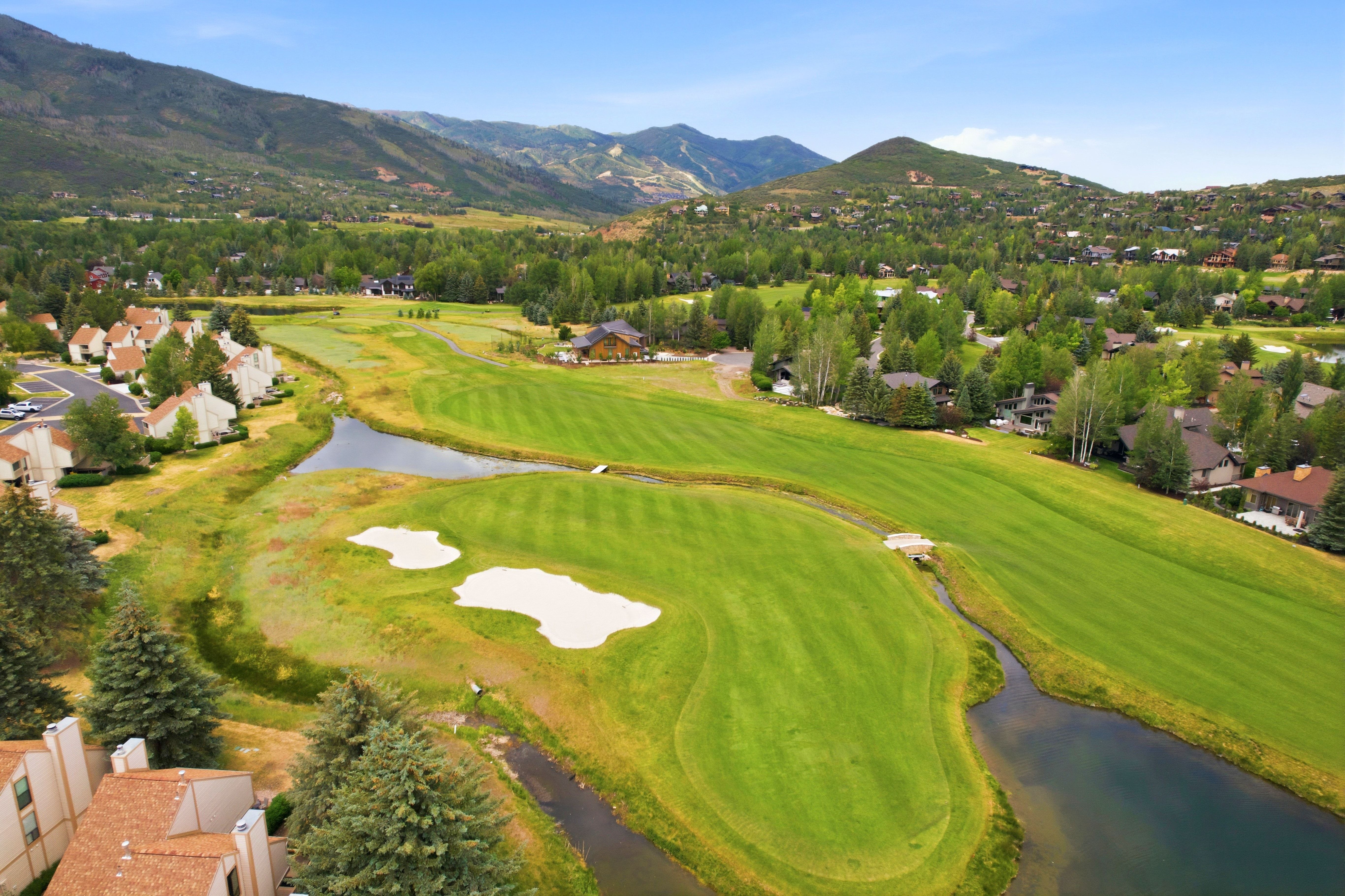 Expansive golf course setting featuring manicured greens, sand bunkers, and water features