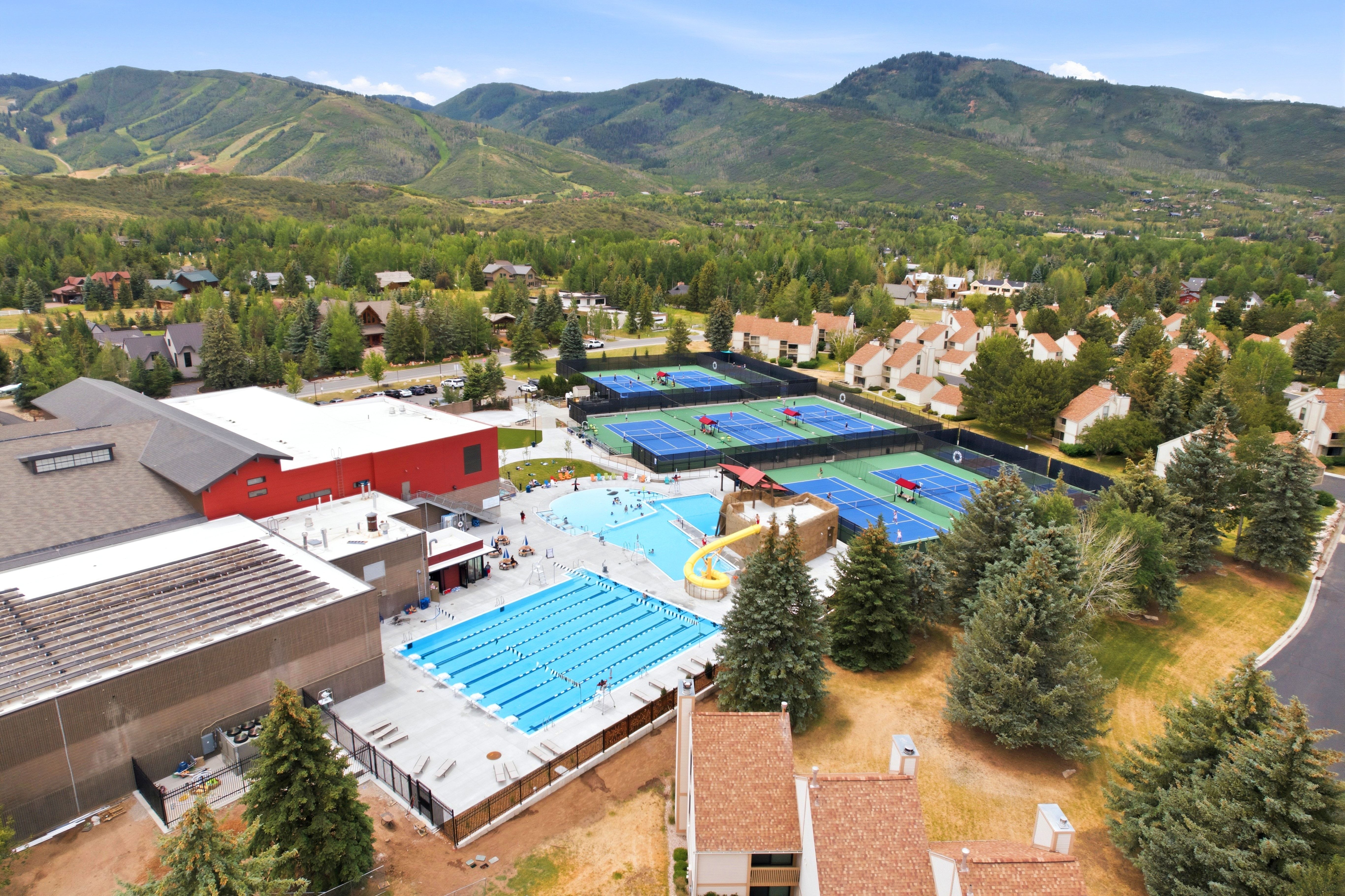 Expansive recreational complex featuring multiple outdoor swimming pools, including a lap pool and a leisure pool with a yellow water slide
