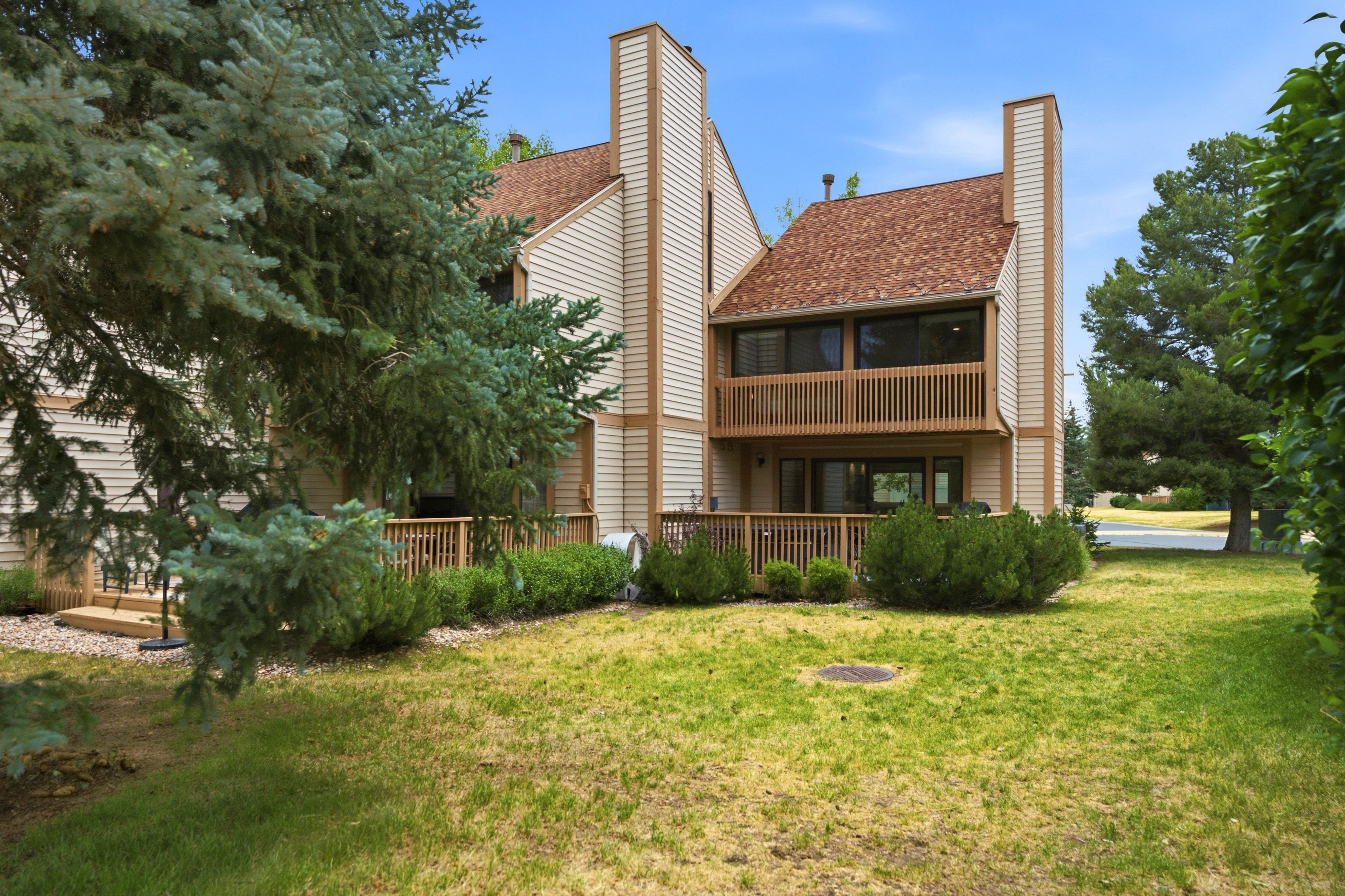 Two-story exterior with light-toned siding, a brown shingle roof, and prominent vertical architectural elements