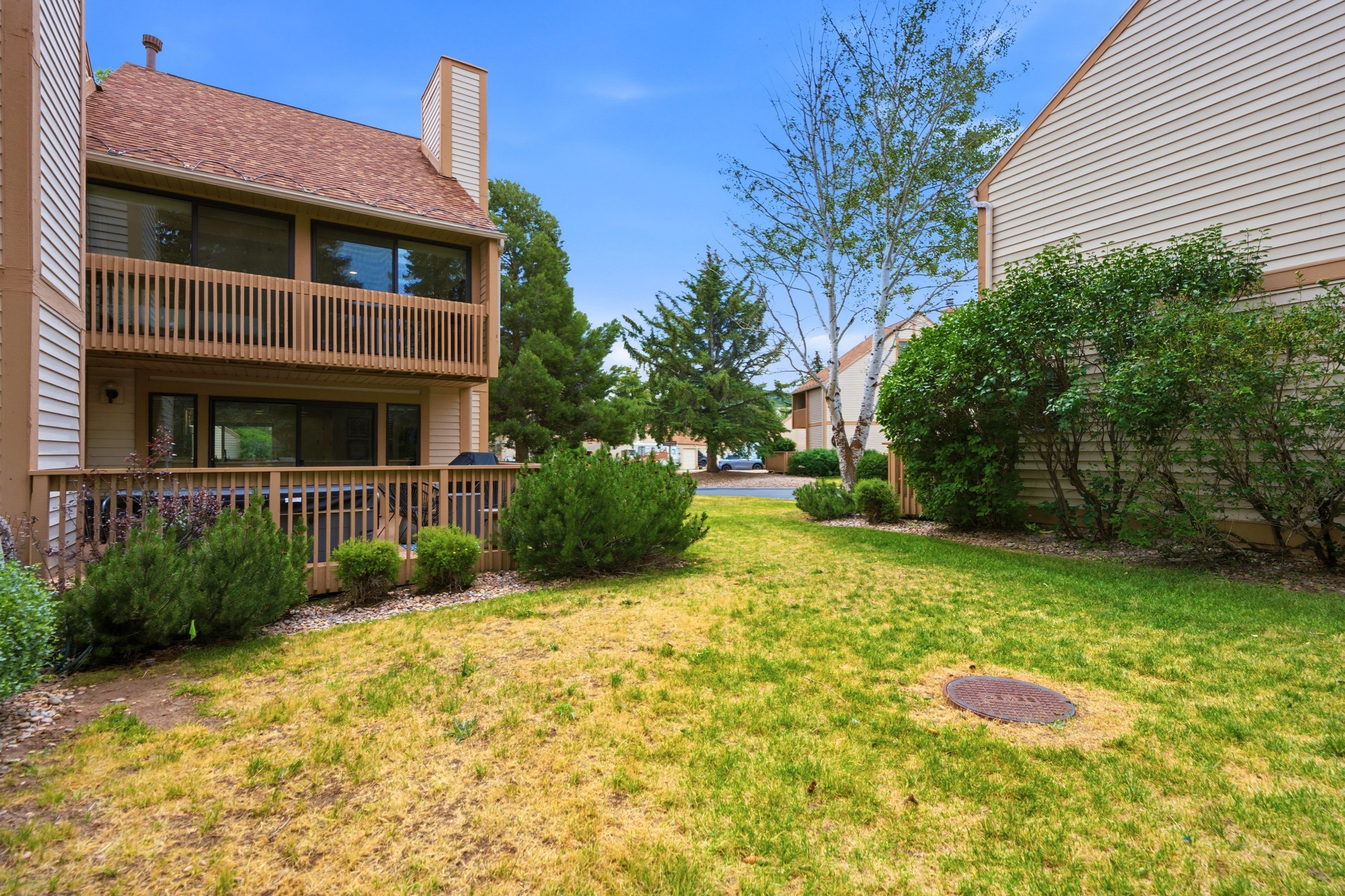 Rear exterior featuring a two-story wood deck, upper-level balcony, and ground-level patio