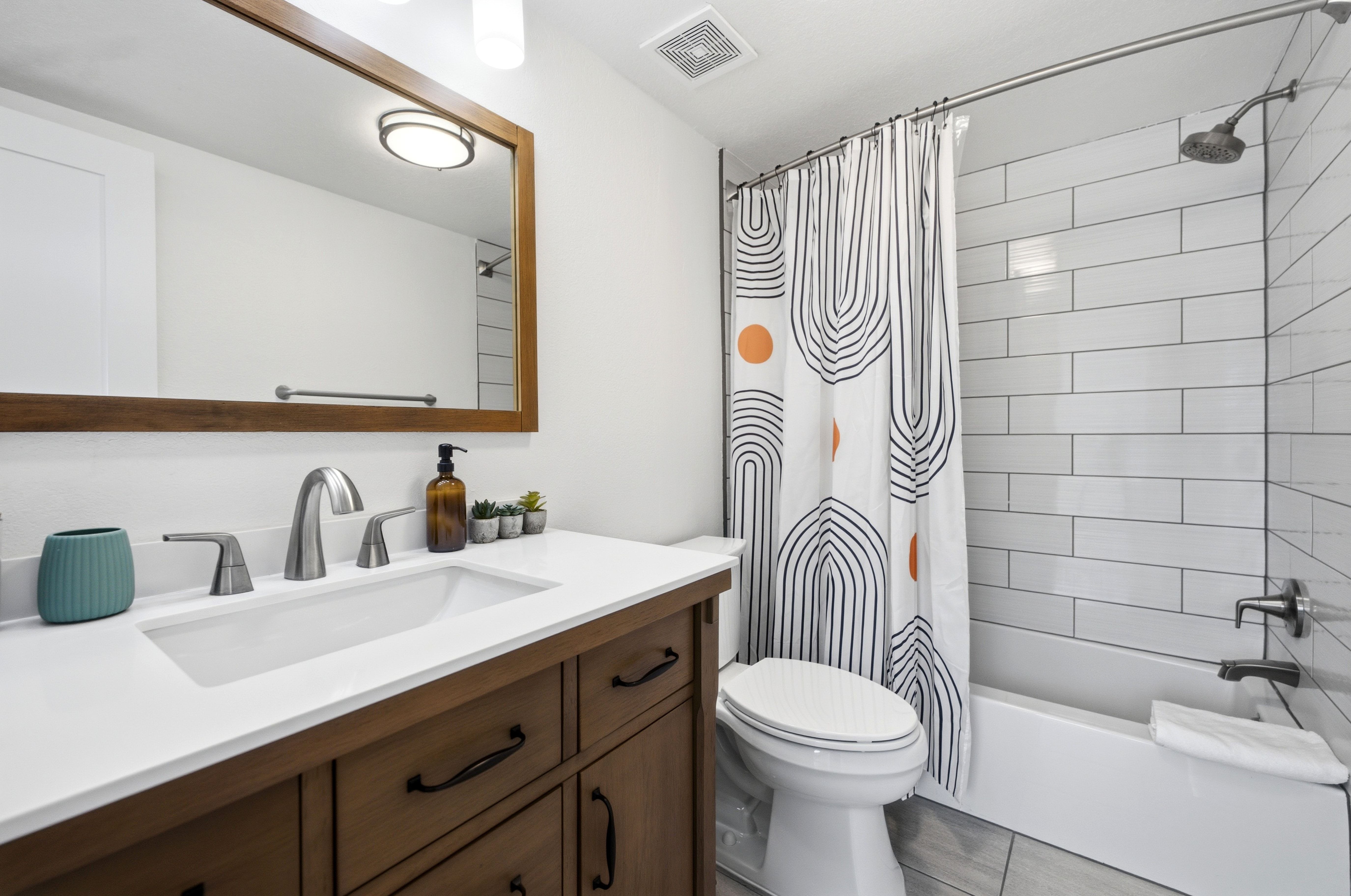 Bathroom featuring a wood-finish vanity with white countertop, undermount sink, and brushed nickel faucet