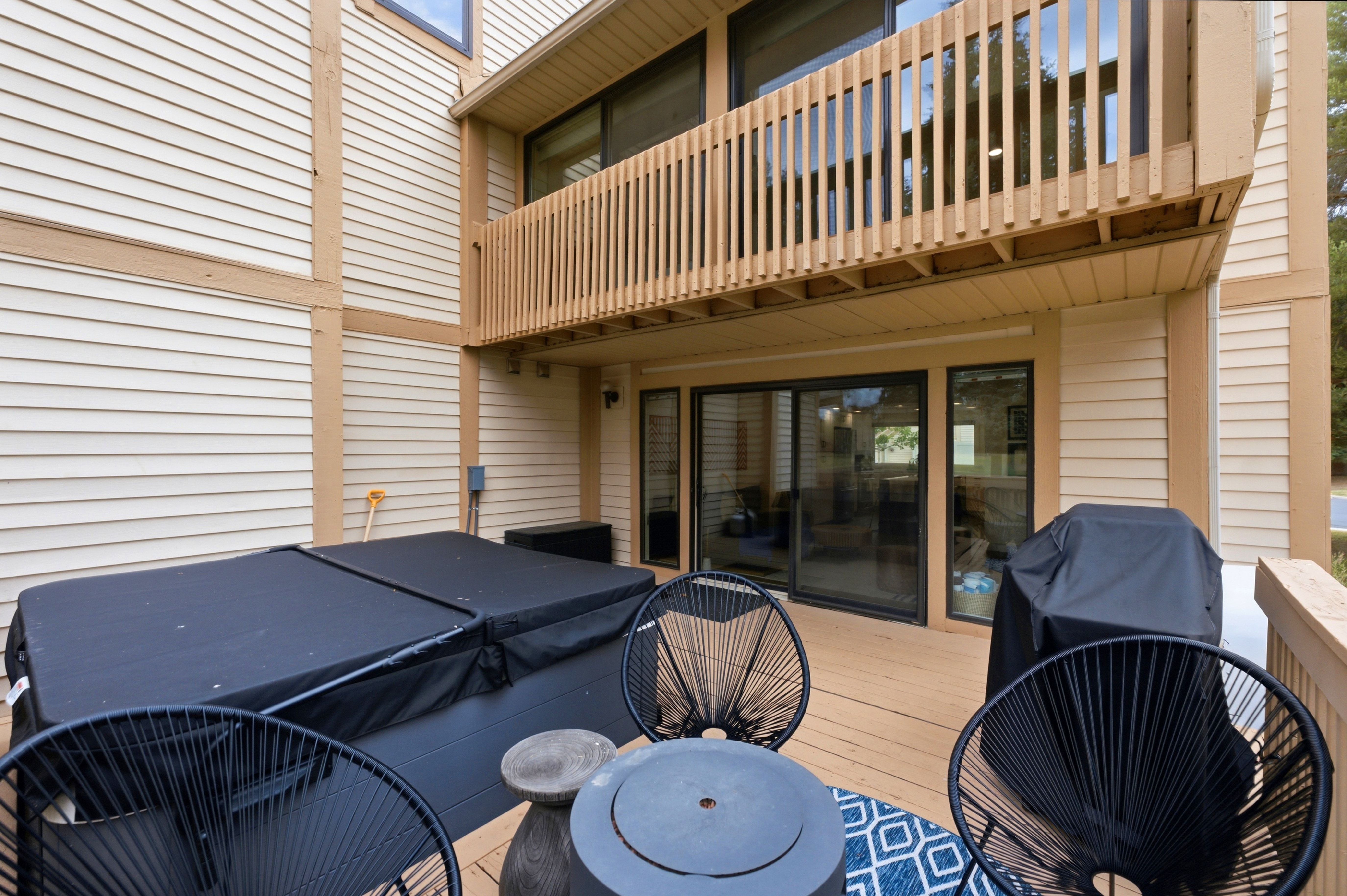 Spacious outdoor deck featuring a built-in spa, sliding glass doors, and a wood-slat balcony above
