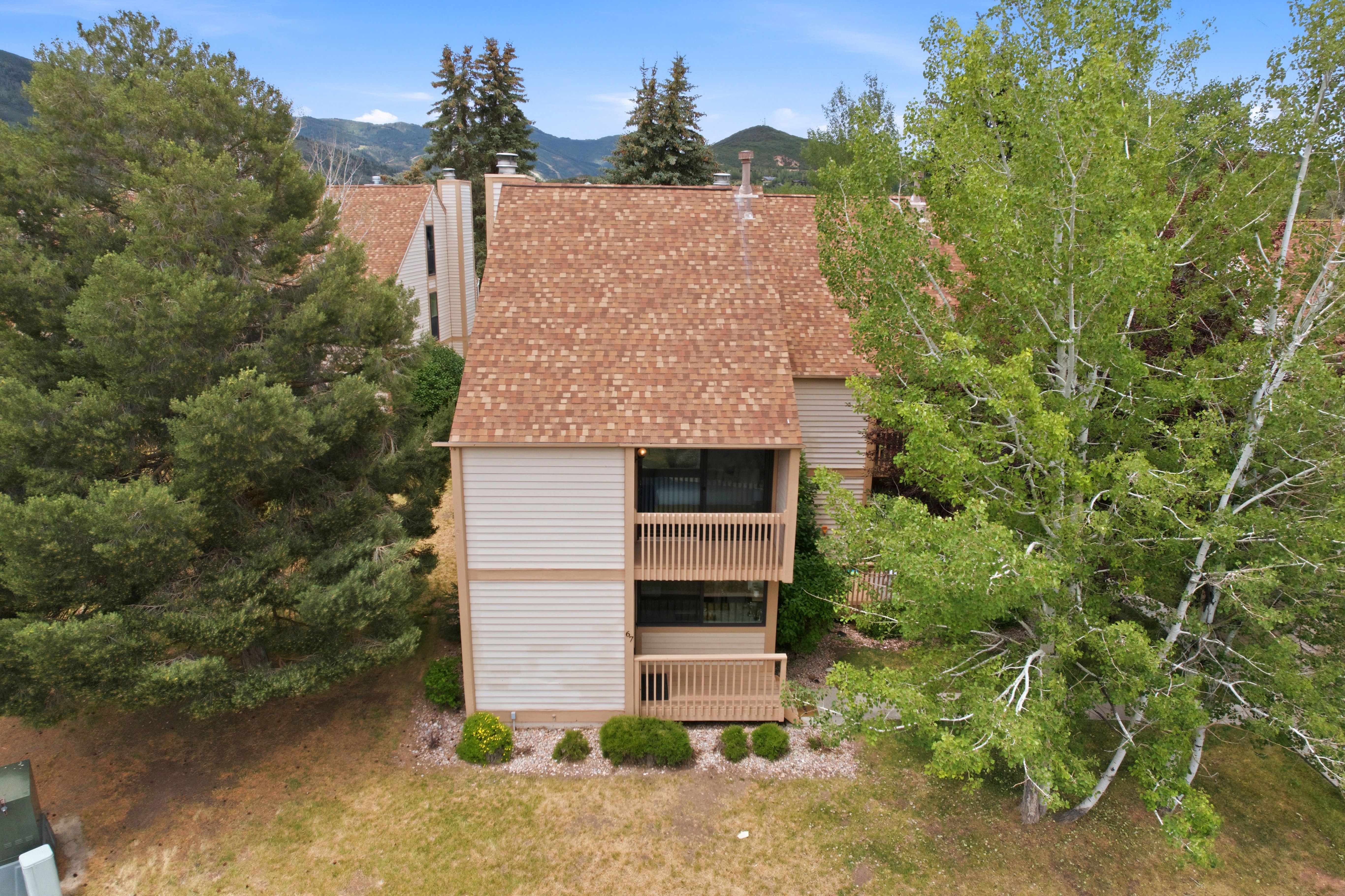 Multi-level property featuring two private wood-railed balconies and a textured shingle roof