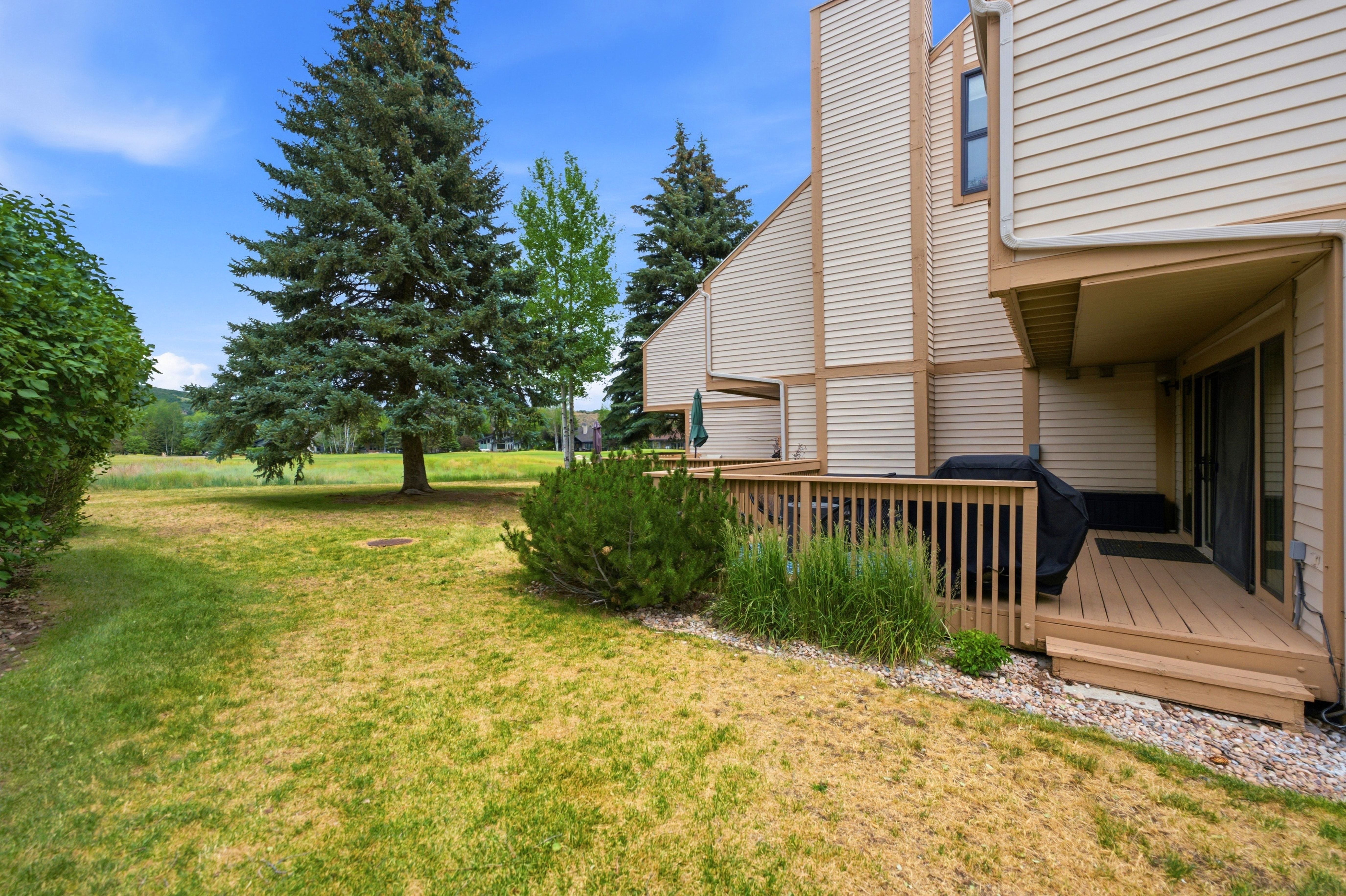 Expansive outdoor deck with wood railing, offering direct access to a grassy yard