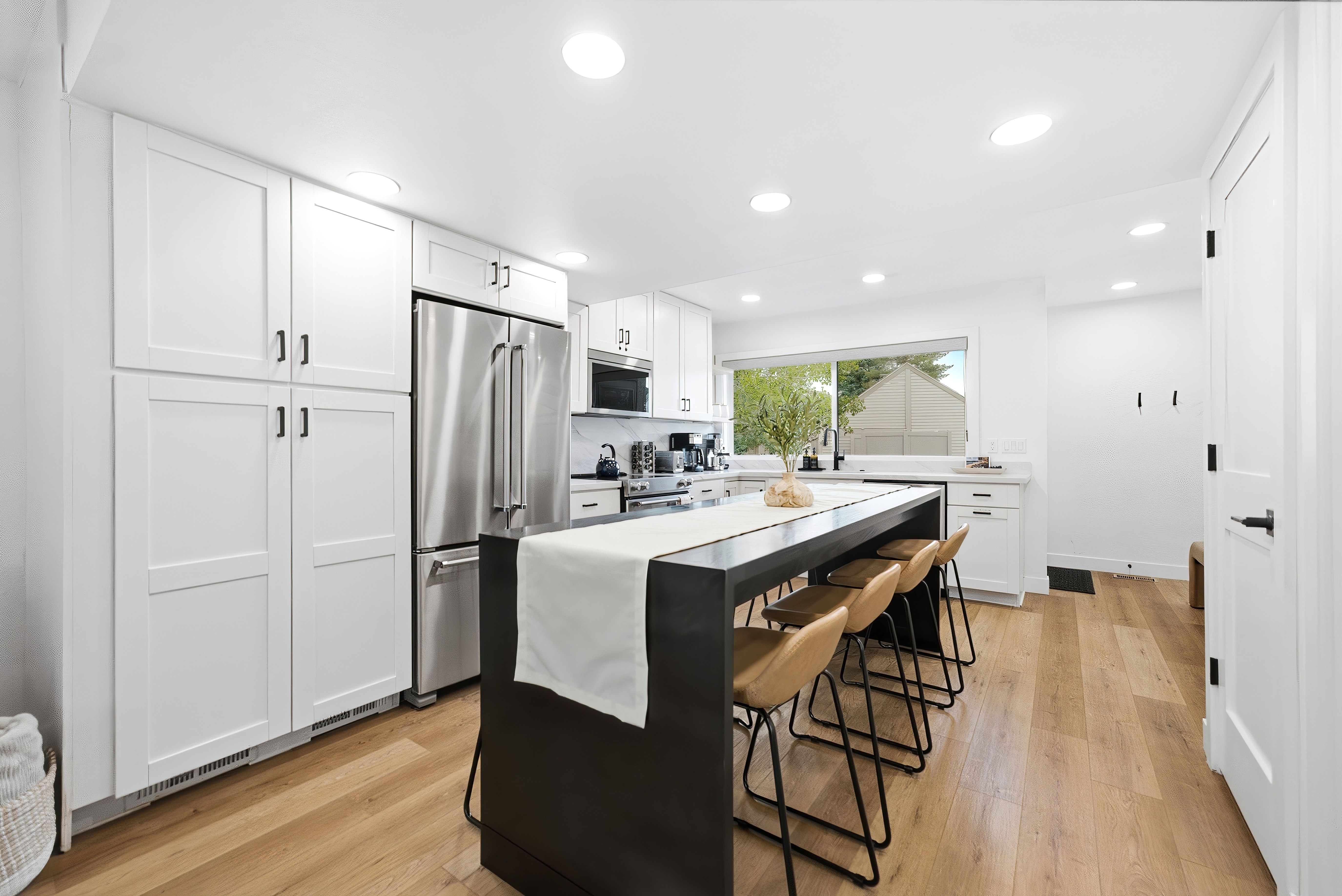 Bright kitchen featuring white shaker cabinetry and wood-finish flooring